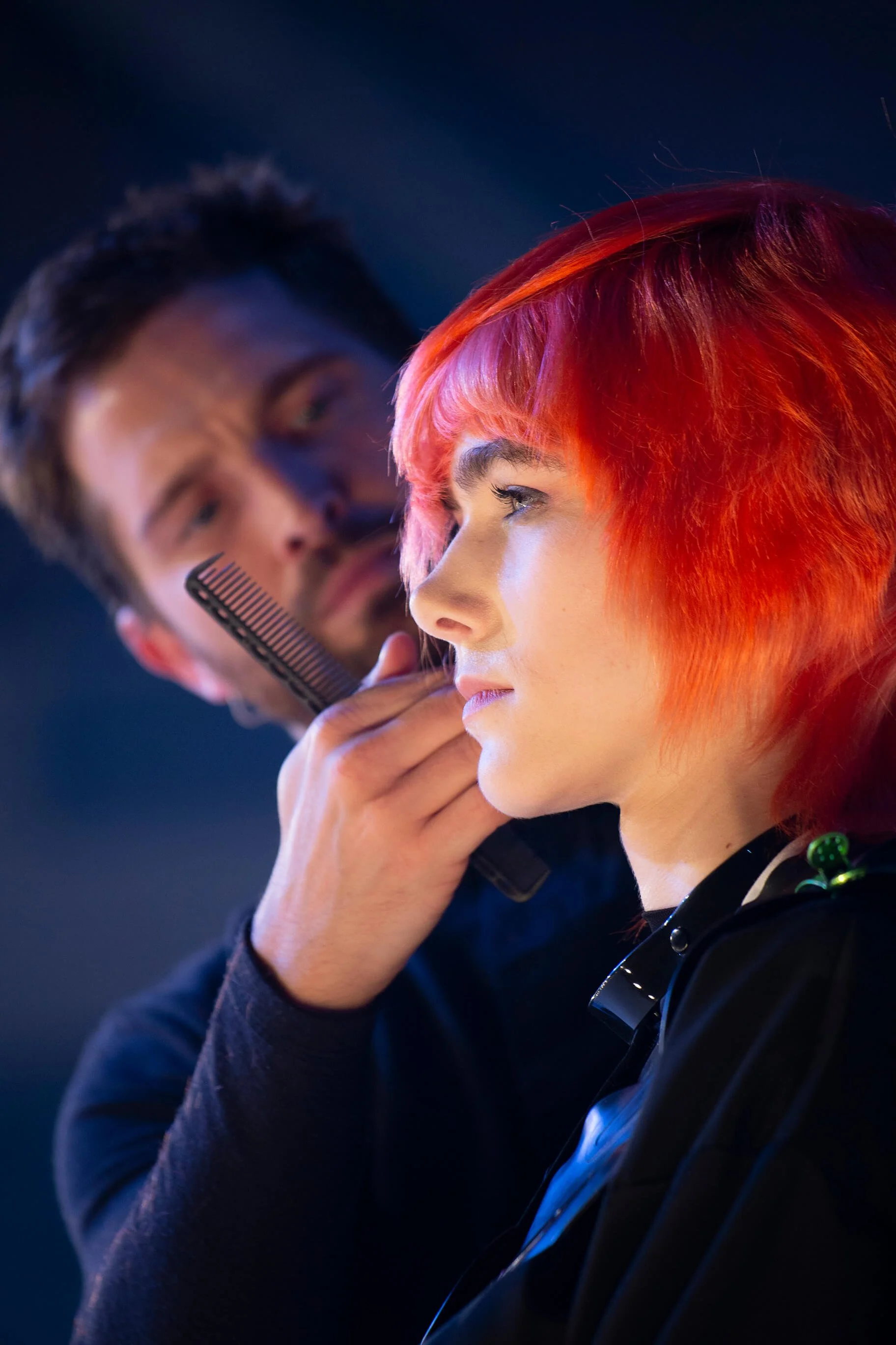 Un photographe professionnel capturant l'art de la coiffure avec des cheveux rouges vibrants.
Styliste coiffant un modèle avec des couleurs de cheveux audacieuses dans un décor artistique.
Gros plan sur un modèle avec des cheveux rouges, mettant en a