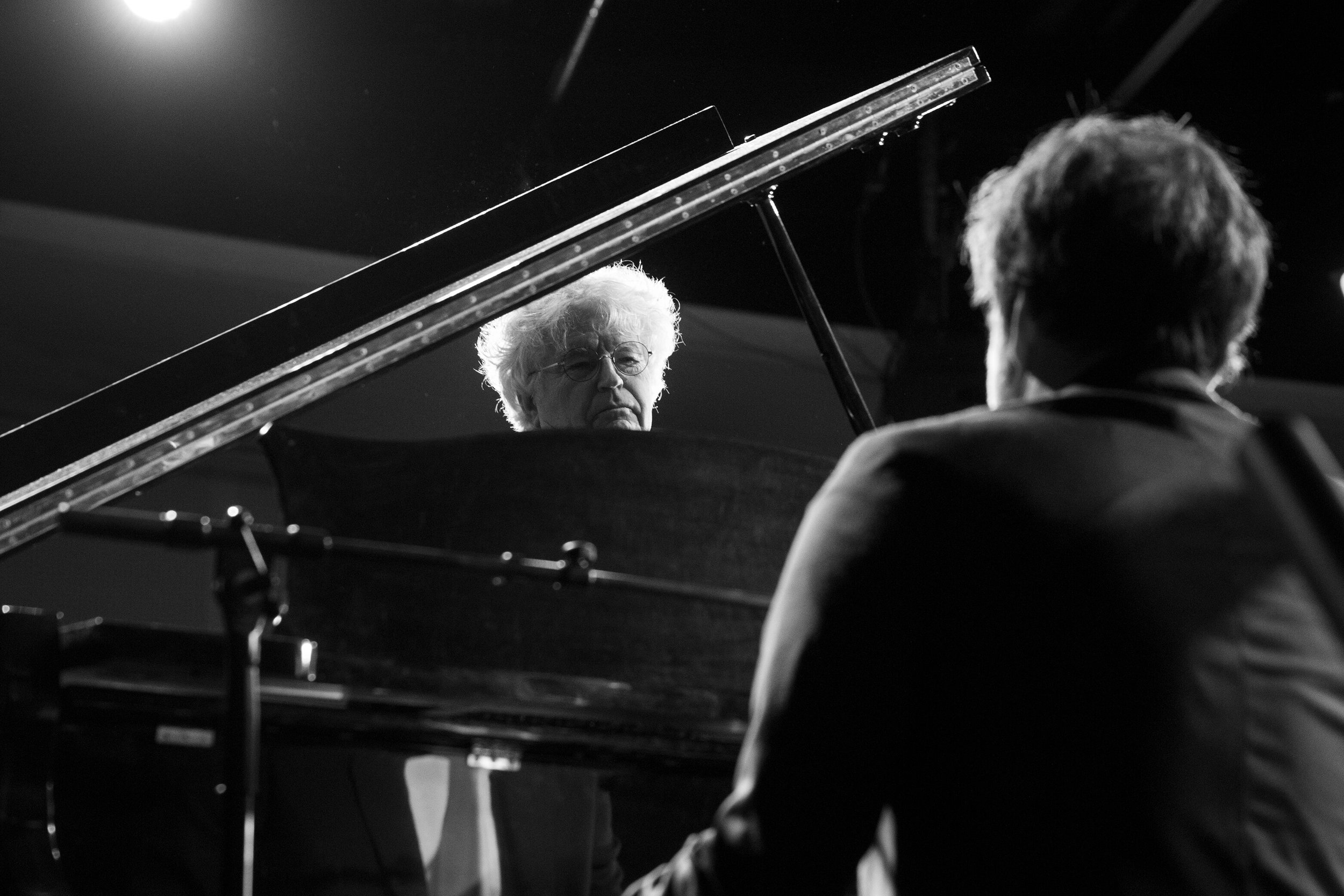 Le photographe François Fauré immortalise un événement musical en noir et blanc.  L’image met en scène un piano, évoquant l’atmosphère d’un concert.  Le noir et blanc accentue les émotions des musiciens.  On aperçoit François Fauré, photographe profe