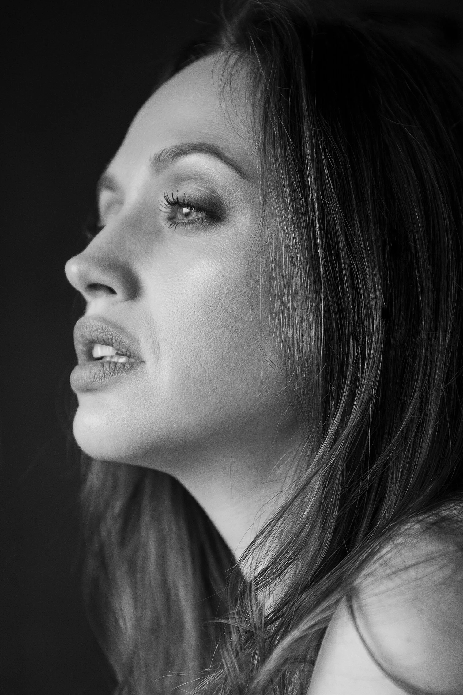 Portrait en noir et blanc d'une femme avec des cheveux longs et foncés, yeux mi-clos, expression calme.