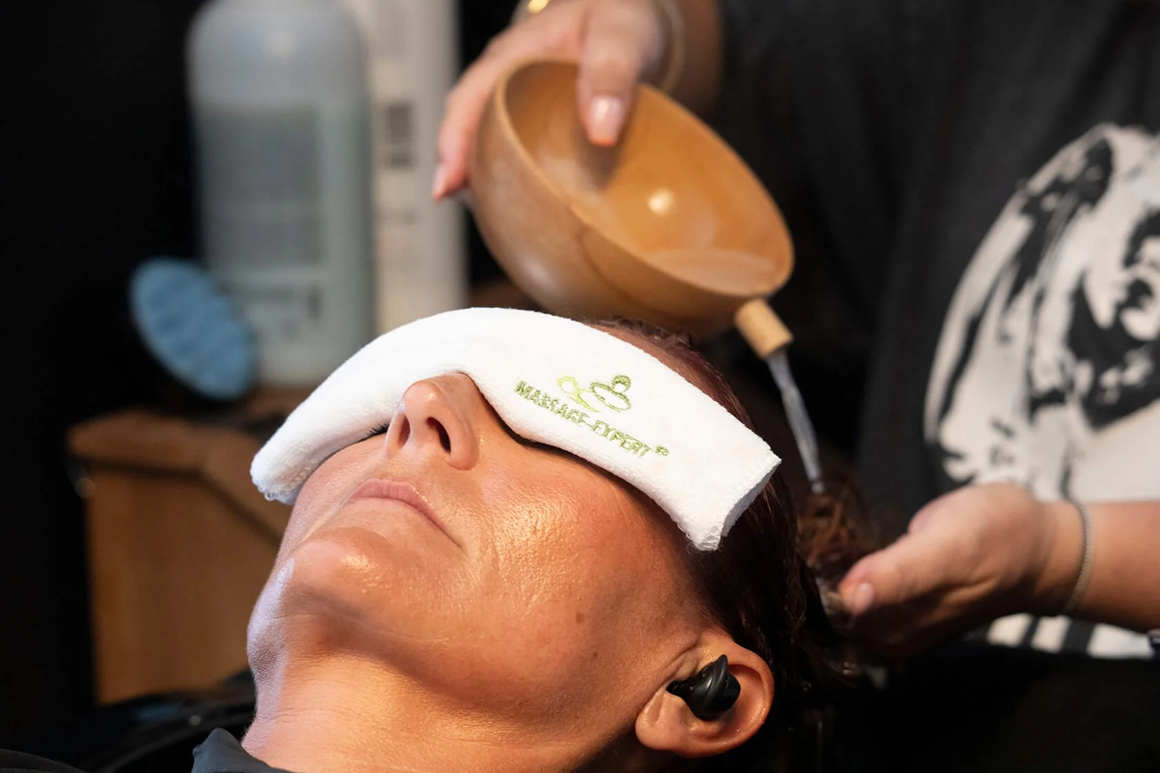 Dans un salon de massage professionnel, une femme reçoit un massage, les yeux bandés. L’ambiance est relaxante, baignée de couleurs apaisantes.  Elle est détendue, profitant pleinement de son soin de bien-être.  Le photographe François Fauré immortal