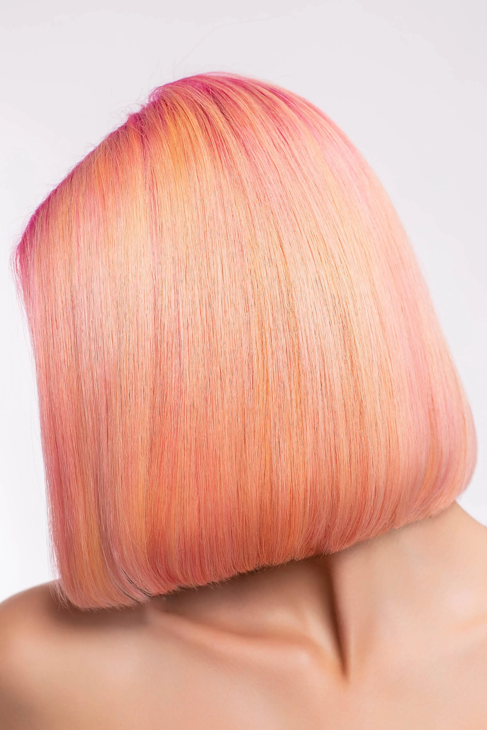 Vue professionnelle d'une coiffure artistique avec des nuances de rose et d'orange.