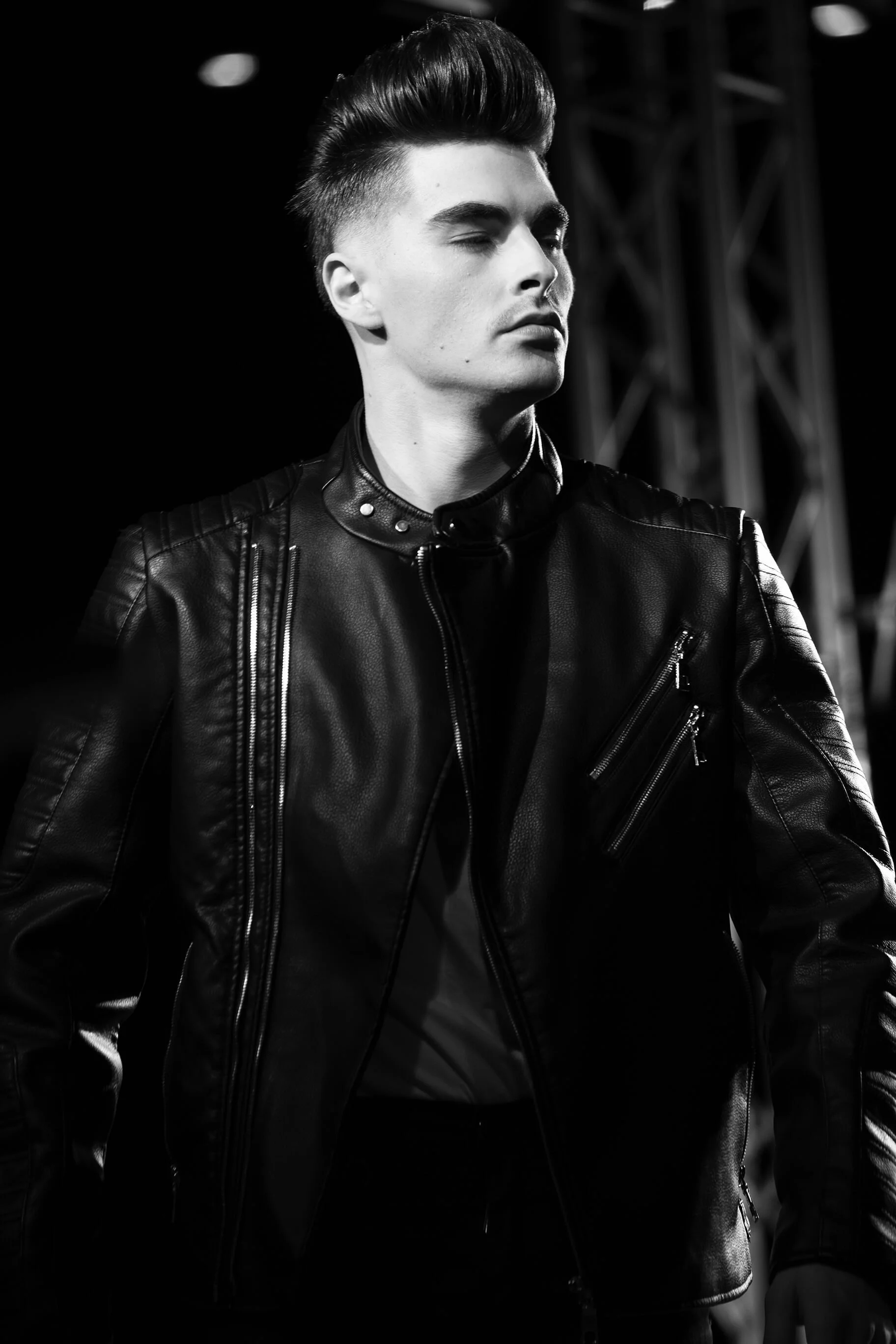 Un modèle avec une coiffure élégante en cuir noir sur un fond sombre.
Vue d'un photographe professionnel sur l'art de la coiffure moderne.
Portrait en noir et blanc d'un modèle avec une coiffure stylée et une veste en cuir.
Décor urbain avec un accen