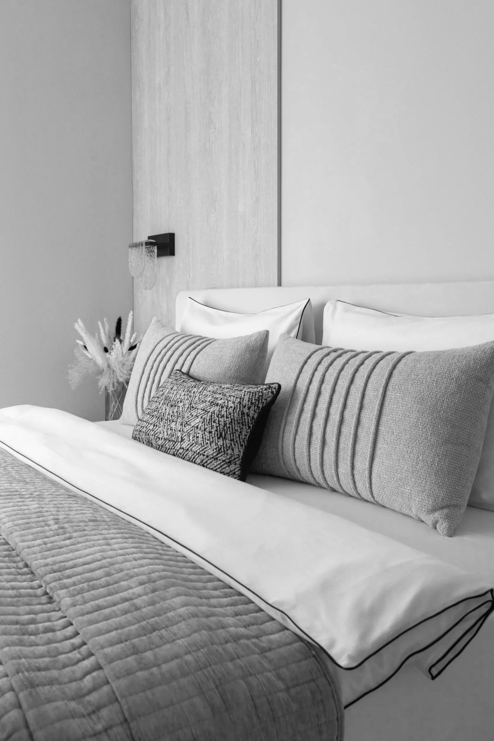 A bedroom with space-themed wall art featuring animals in space, planets, stars, and a rocket. The bed has multiple pillows and a crescent moon plush with a smile. Two bedside tables with lamps, toys, and a framed photo are present.