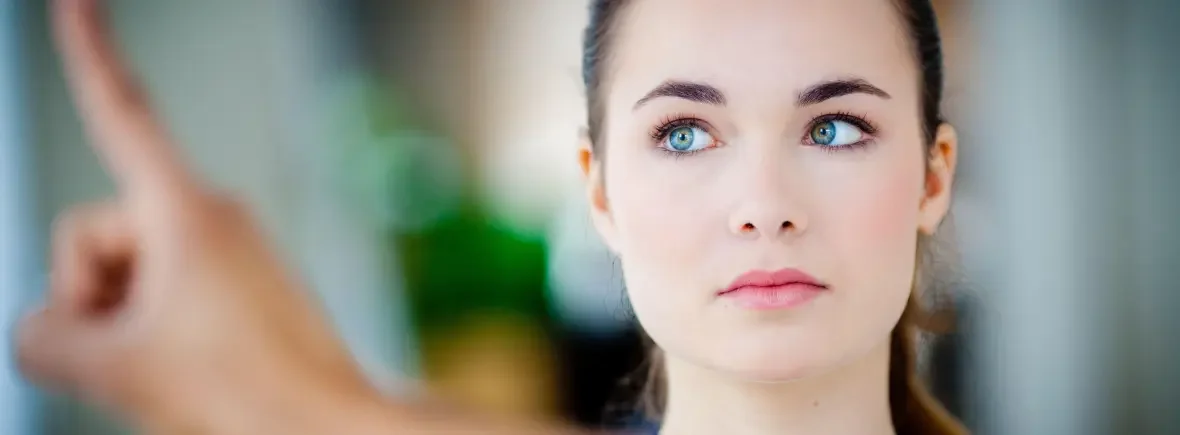 A young woman with blue eyes and dark hair looking to the side with a neutral expression.
