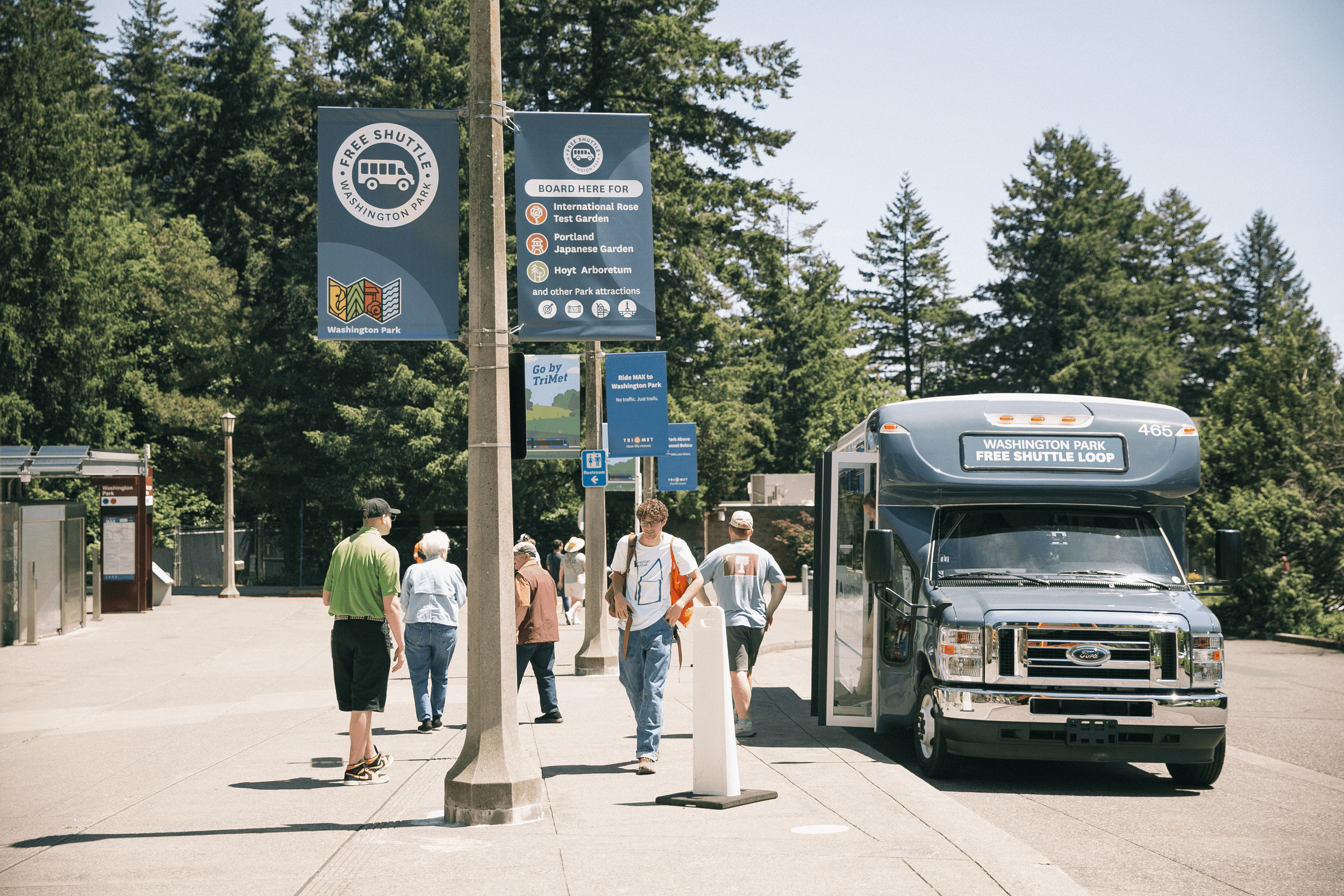 Visitors boarding the Washington Park Free Shuttle Loop bus at a marked stop.