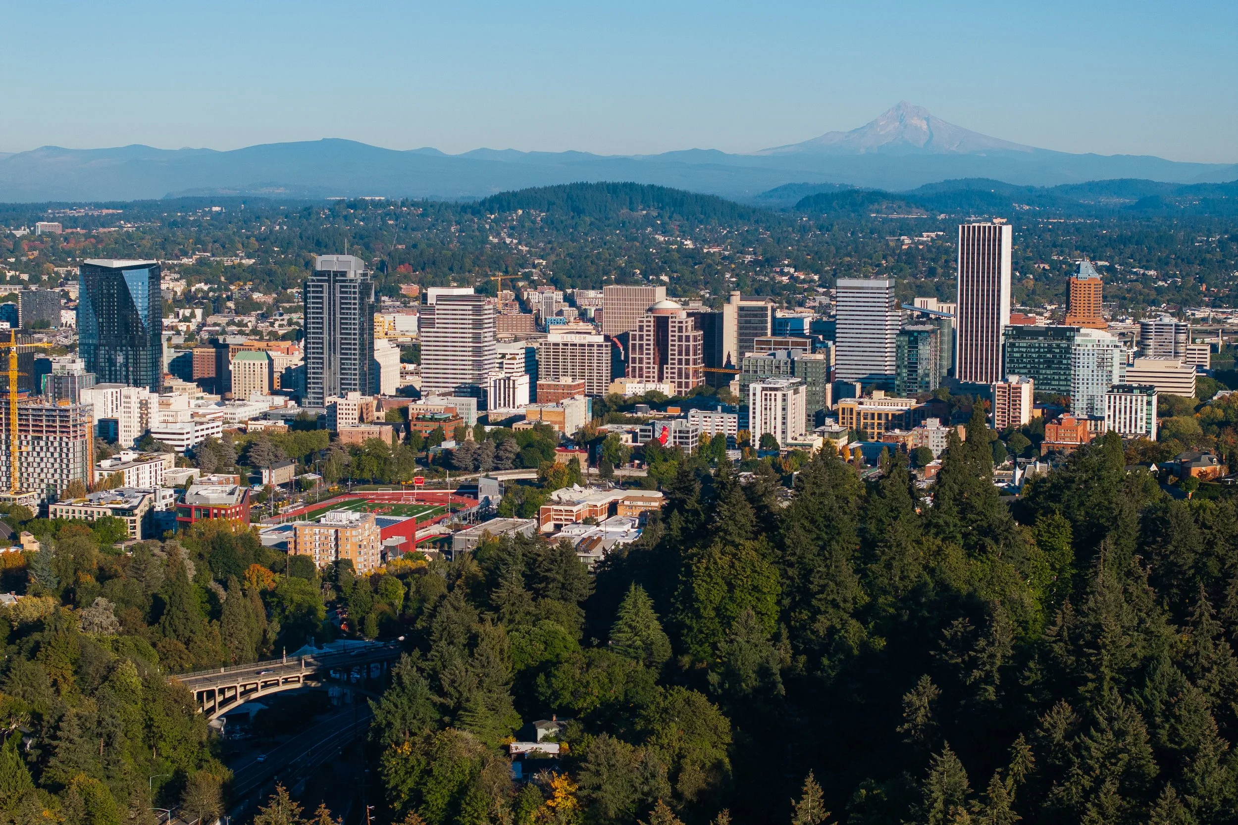 View of downtown Portland with Mount Hood in the distance, next to driving directions to the Park.