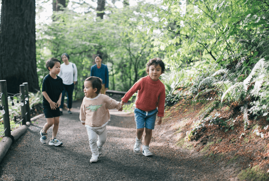 A family with young children walking along a lush forested trail in Washington Park
