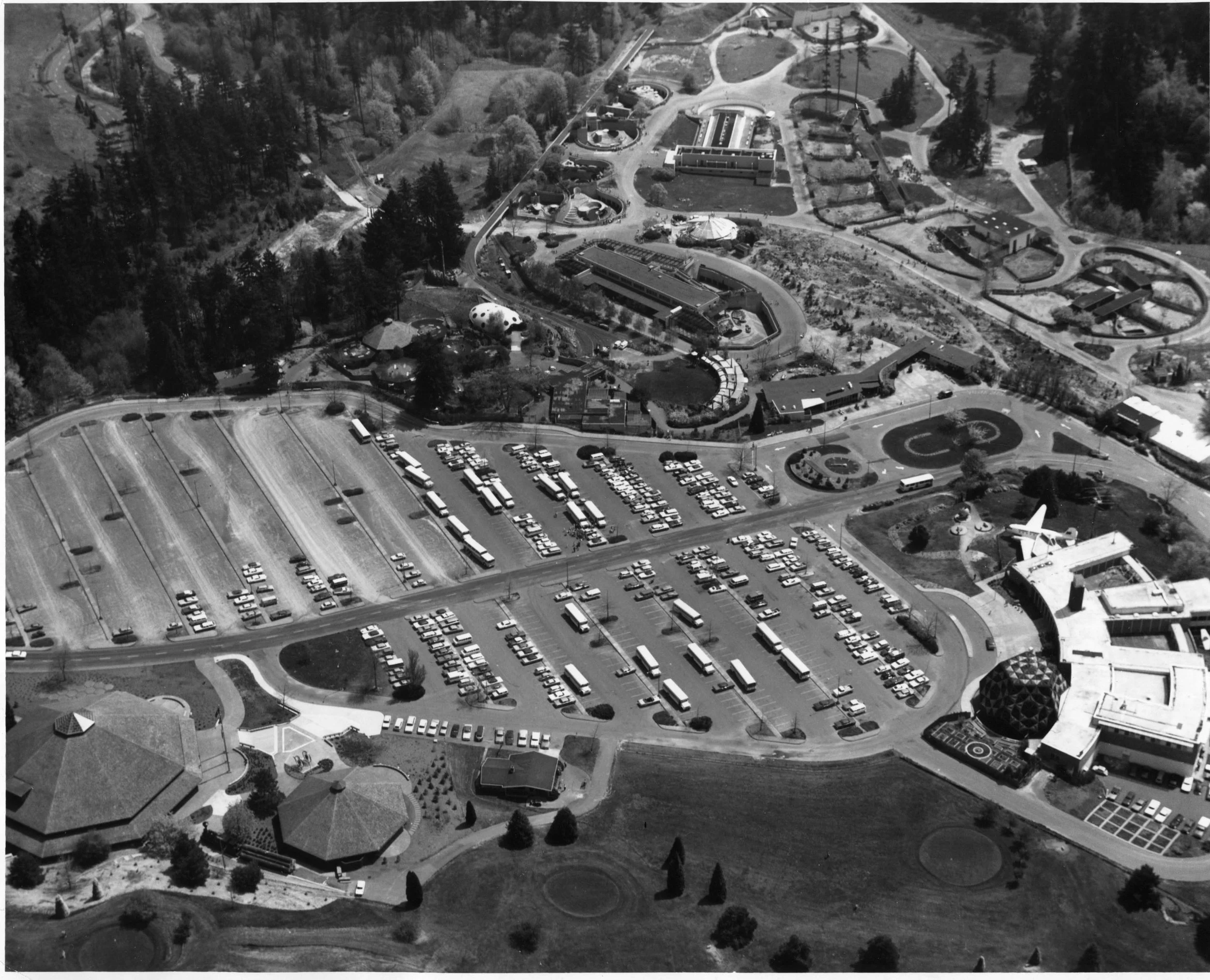Mark Reed - Zoo & World Forestry Aerial (1970s) - Black-and-white 1970s aerial photo of the Oregon Zoo grounds, showing animal enclosures, winding paths, and a large parking lot