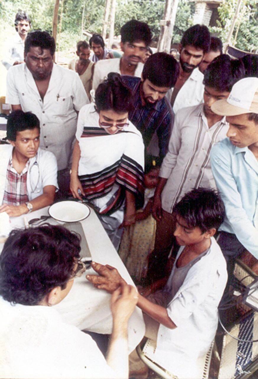 Medical professionals and a boy in a rural outdoor setting during a medical check-up or vaccination event.
