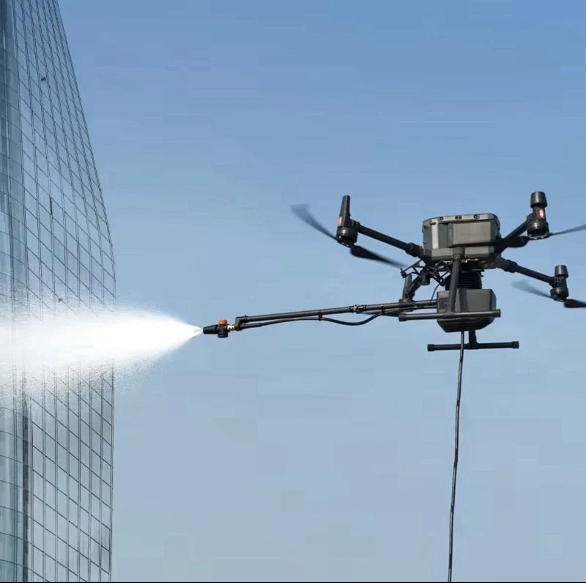 A drone spraying water on a skyscraper under clear blue sky.