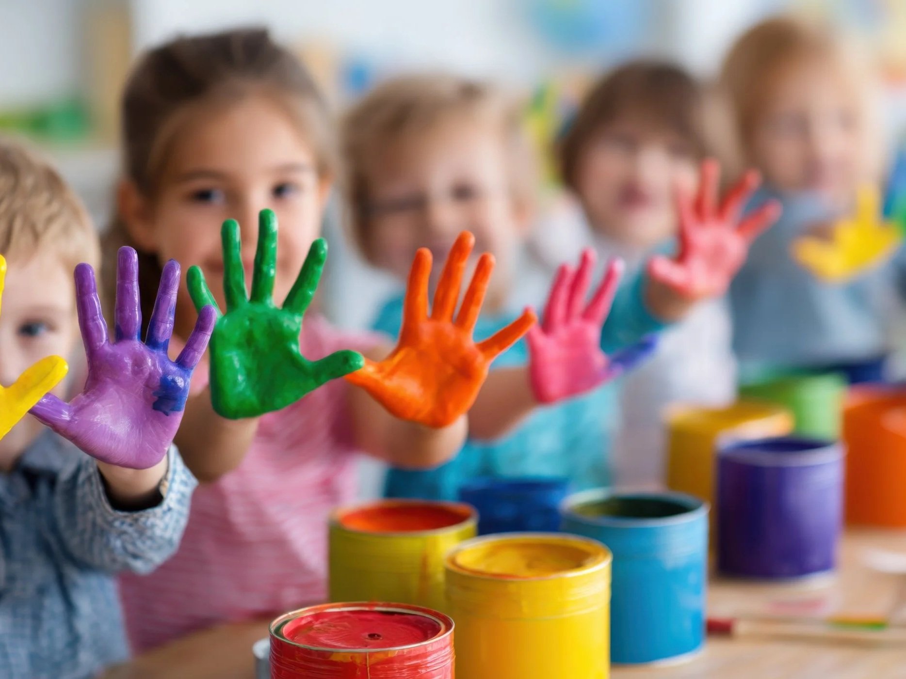 Children showing colorful painted hands during an art activity at Peralta’s Playhouse daycare.