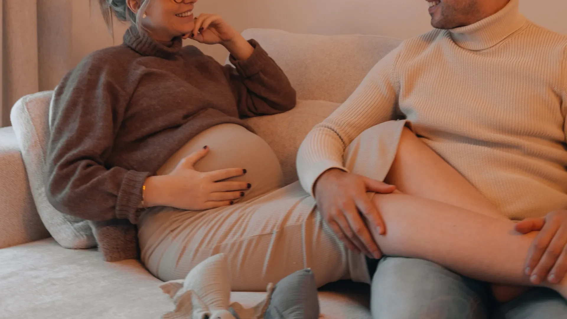 Pregnant couple relaxing together on a couch, connecting before the birth of their baby during private birth preparation sessions
