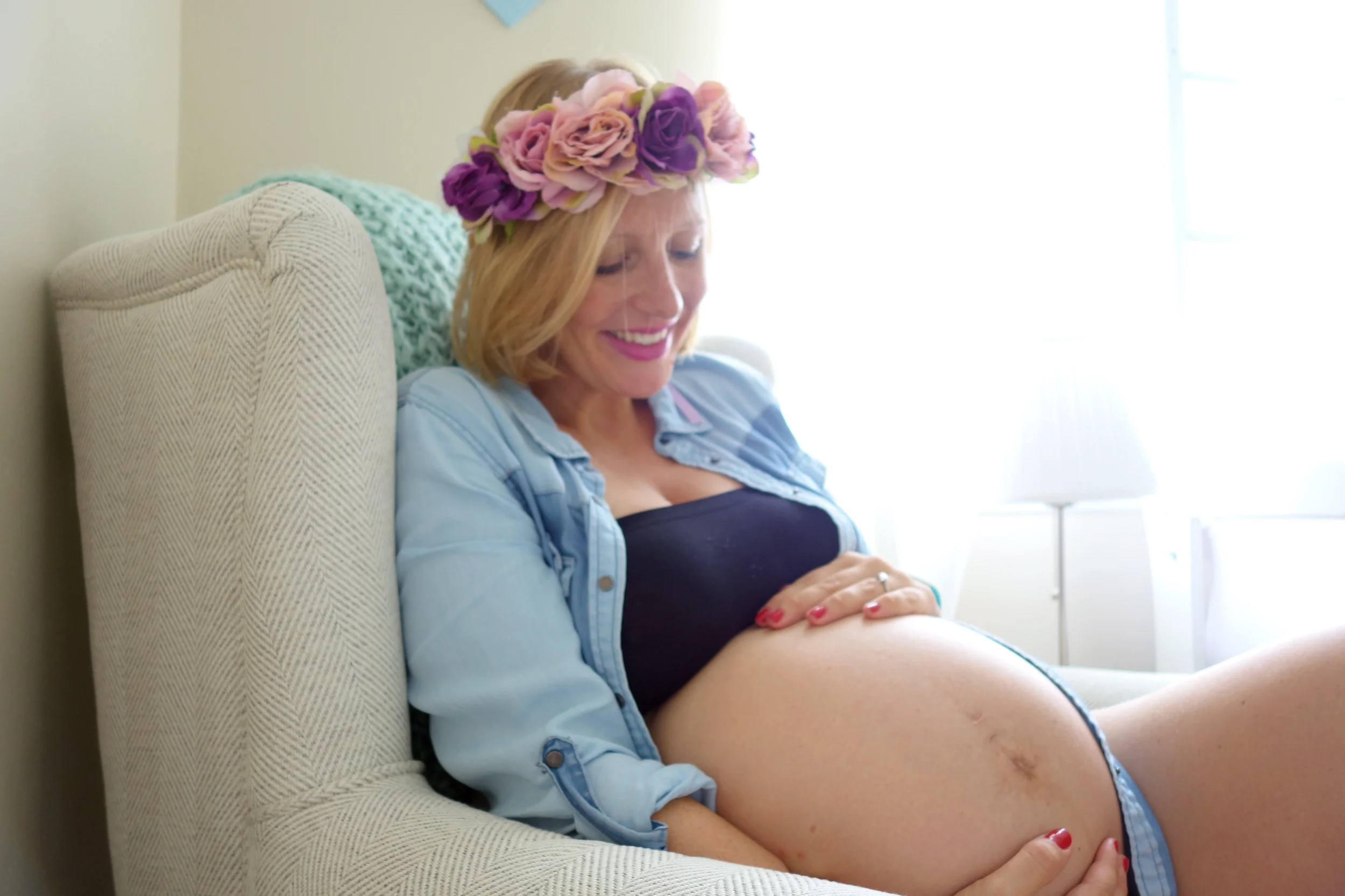 Smiling pregnant woman with a flower crown cradling her baby bump — celebrating a confident, positive birth preparation journey