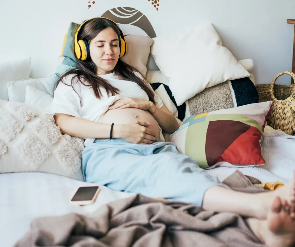 A pregnant woman relaxing on her bed listening to a guided relaxation from the BrightBirths antenatal course