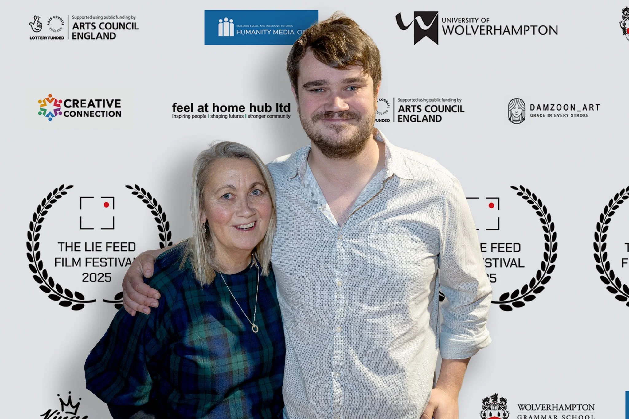 A woman and a man standing together at the 2025 The Lie Feed Film Festival, smiling, with various sponsor logos in the background.