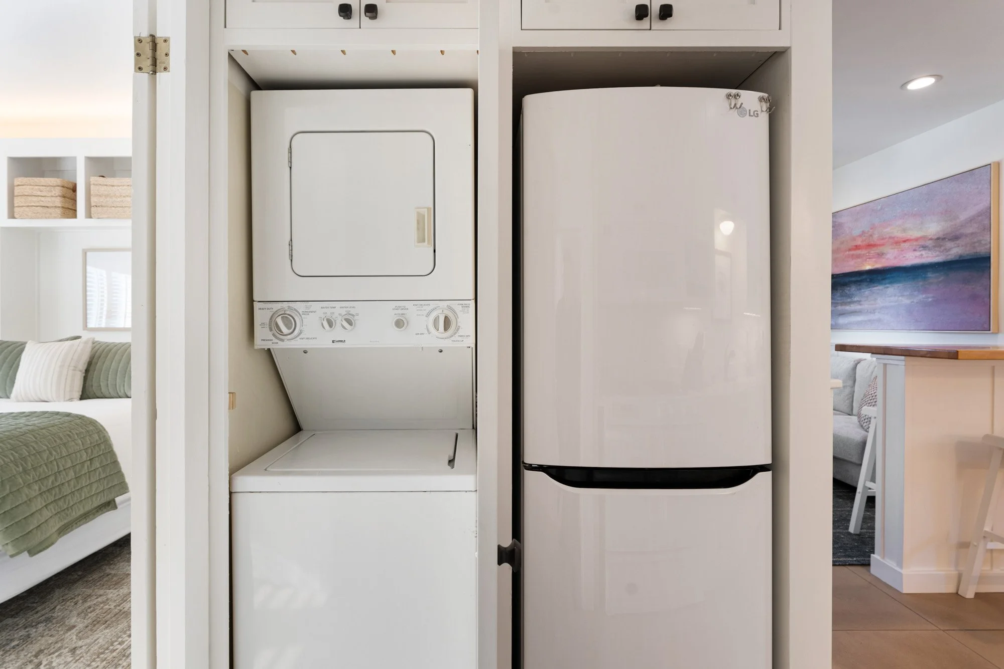 Laundry area with stacked washer and dryer next to a refrigerator in a kitchen or laundry room.