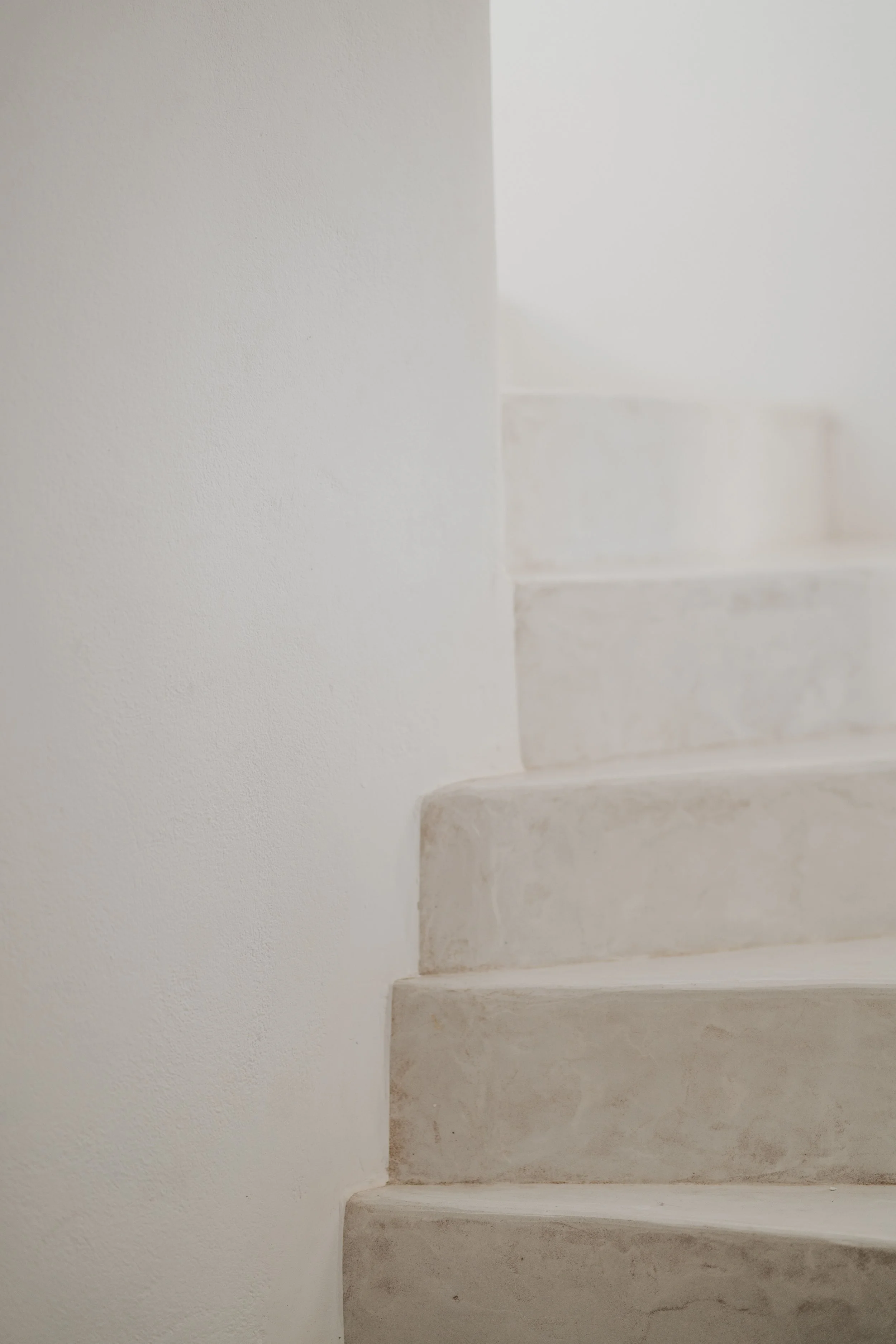 White marble stairs with a smooth finish, adjacent to a plain white wall.