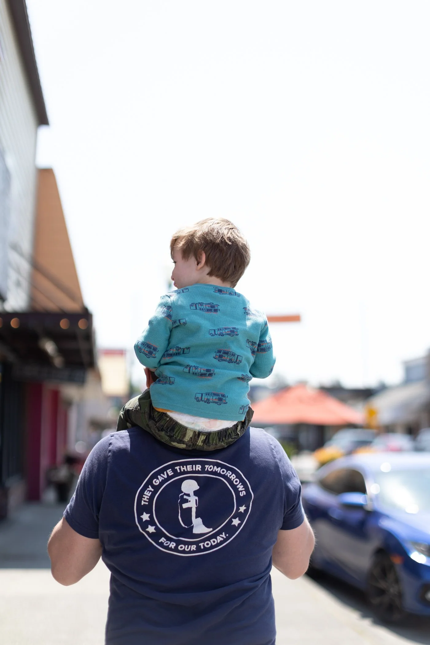 Toddler boy riding on his father shoulders walking through downtown Arlington, WA