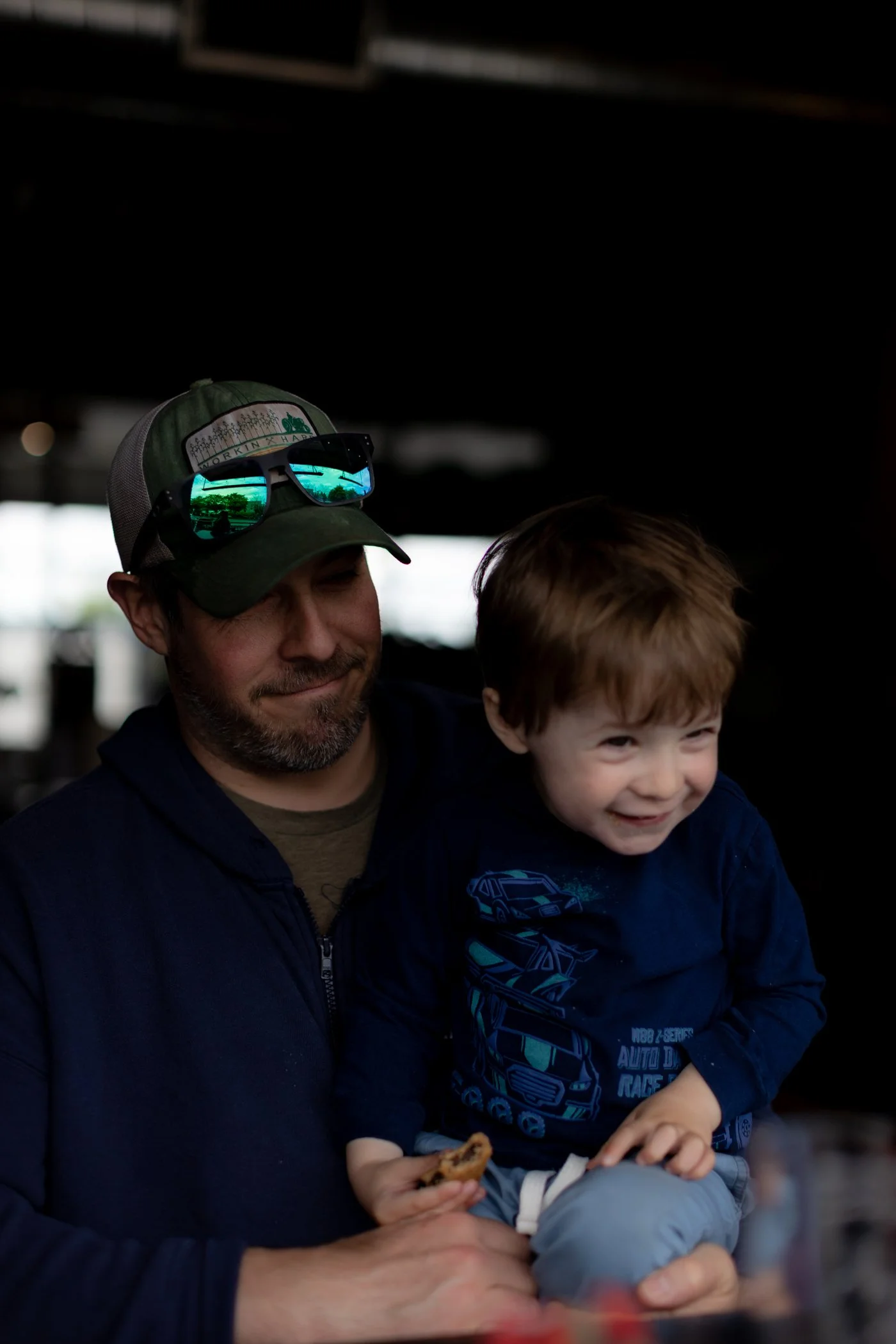 Father holding toddler son who is eating a snack at In The Shadow, a brewery in Arlington, WA