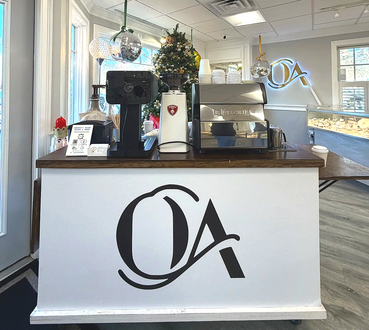Coffee bar with espresso machine, coffee grinder, Christmas tree, and decorative ornaments in a cafe.