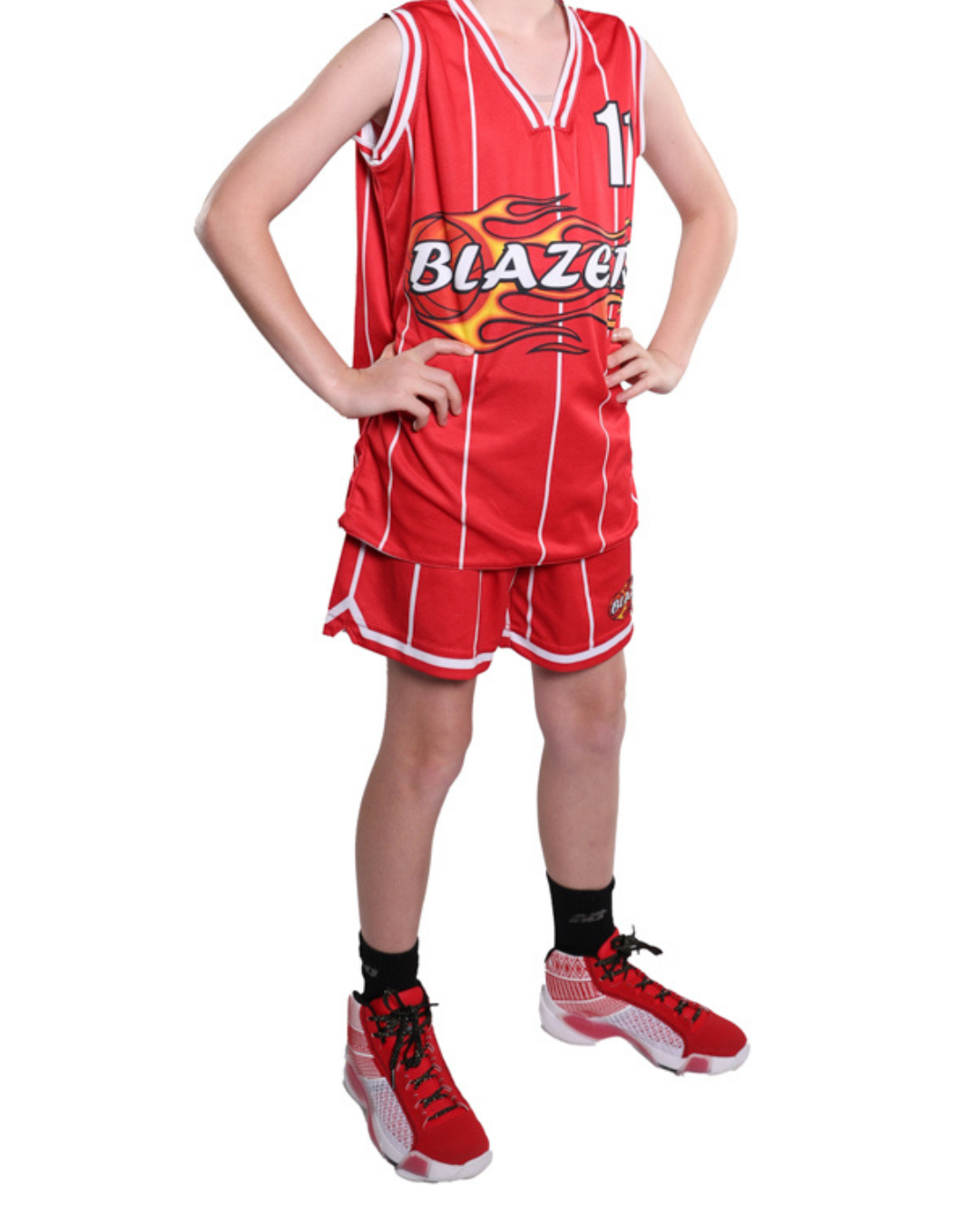 A young person wearing a red basketball uniform with white vertical stripes, black socks, and red and white athletic shoes, standing with hands on hips.