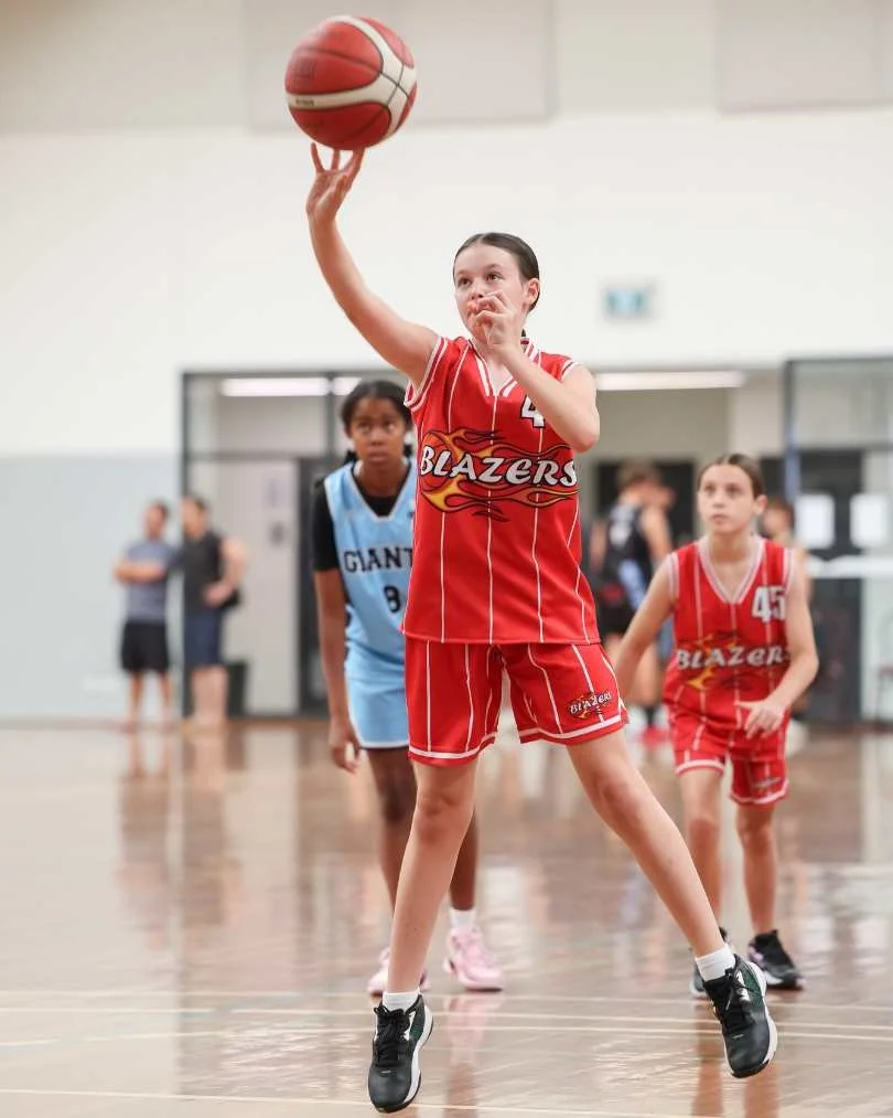 A young girl in a red basketball uniform with