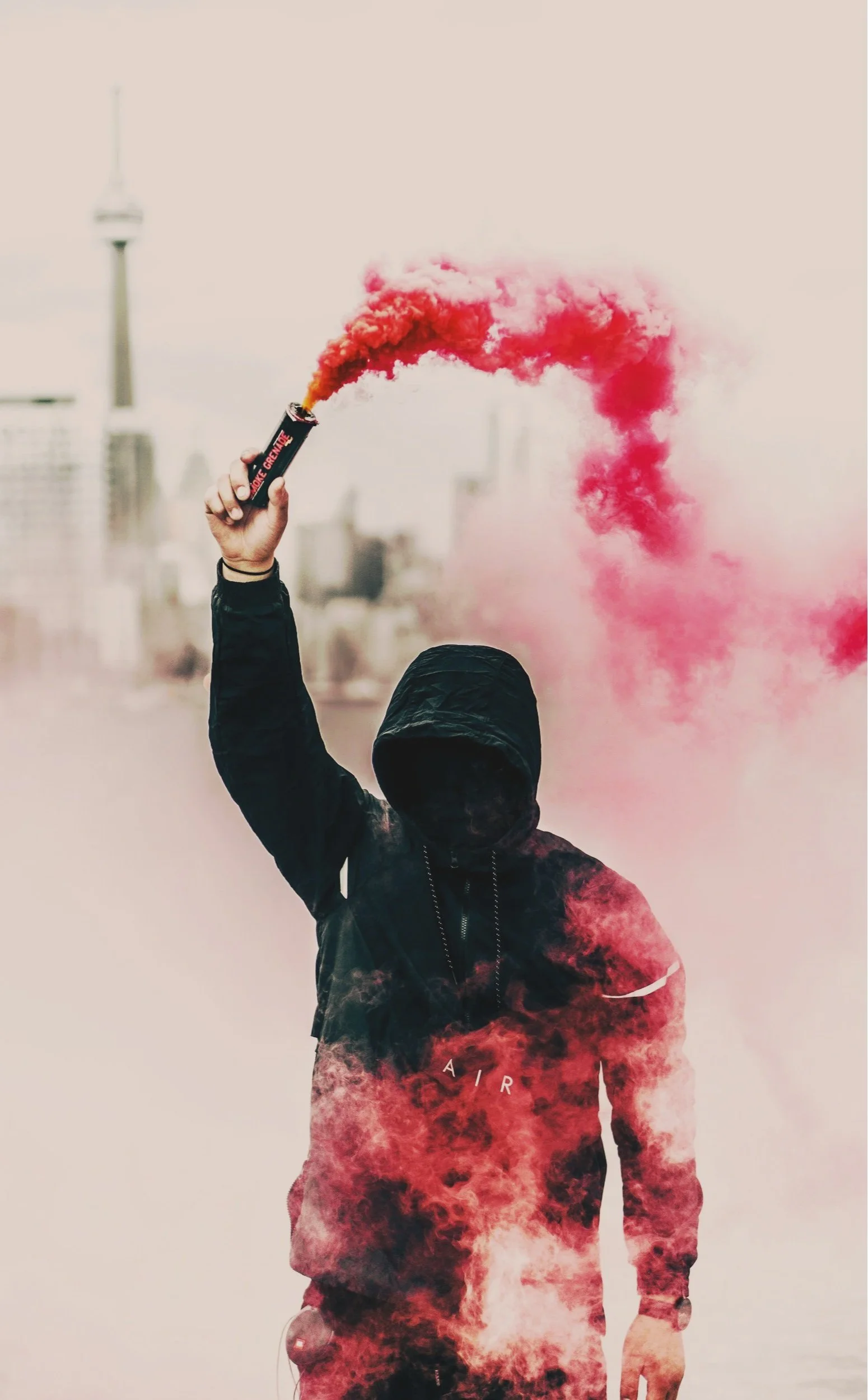 A faceless man holds a red smoke grenade