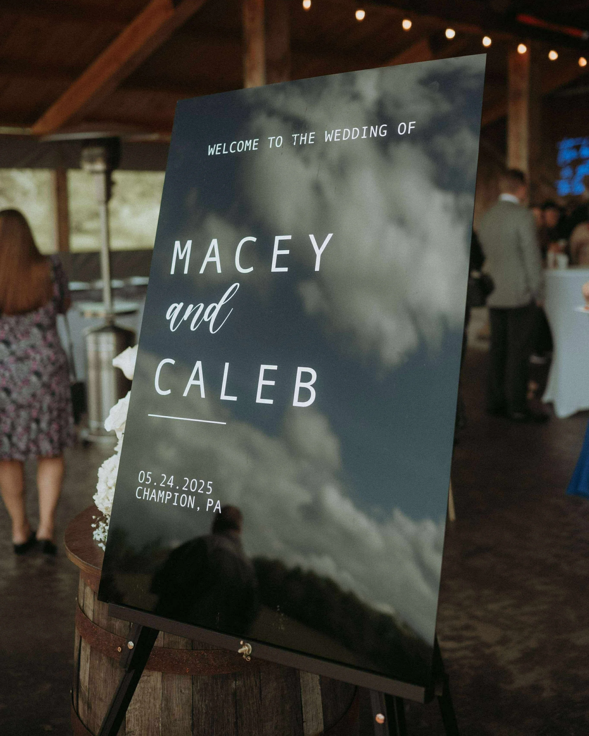 Wedding sign with a cloudy sky background welcoming guests to the wedding of Macy and Caleb, held on May 24, 2025, in Champion, PA.