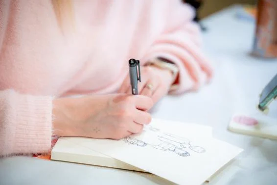 Person drawing on paper with a black pen