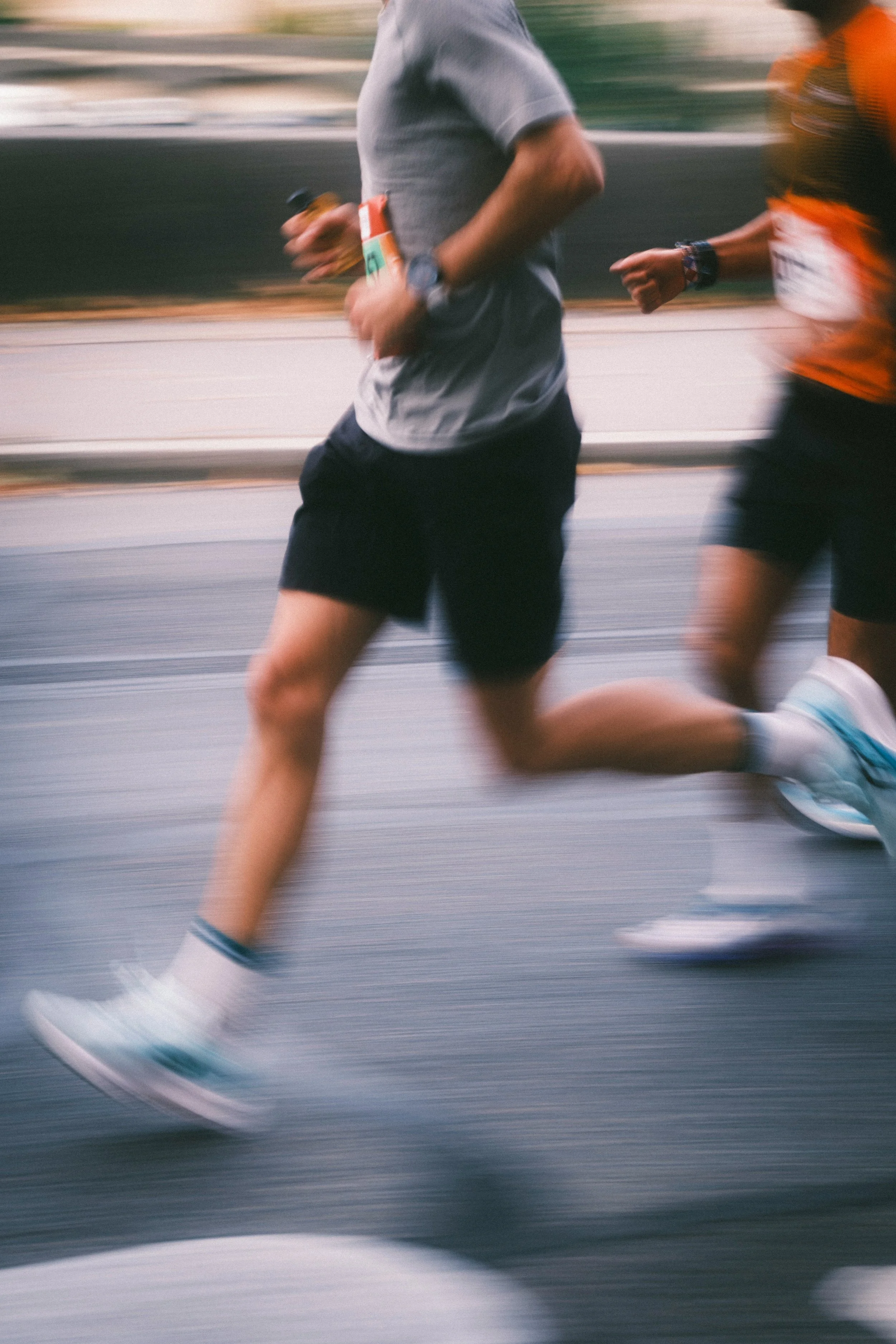 Two runners jogging on the street, mid-stride, wearing athletic gear.
