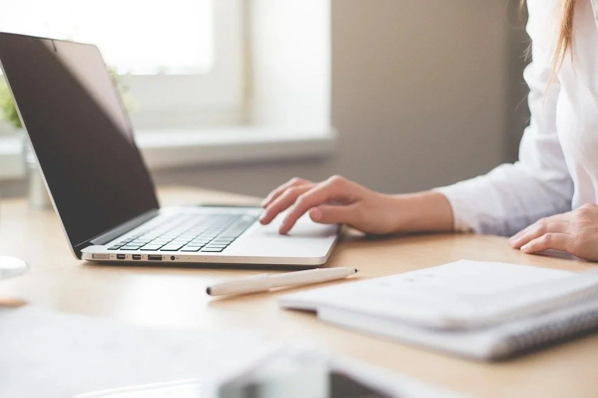 Computer with girl typing and notebook and pen
