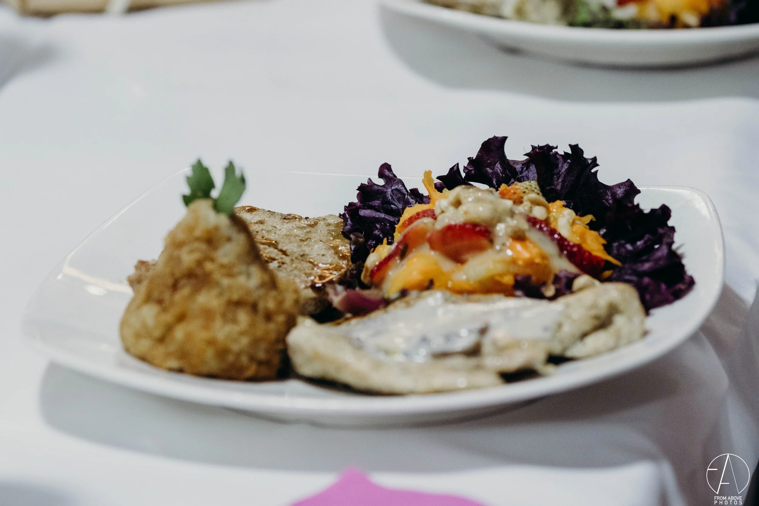 Plato de comida con ensalada, pollo frito y otros acompañamientos en un plato blanco
