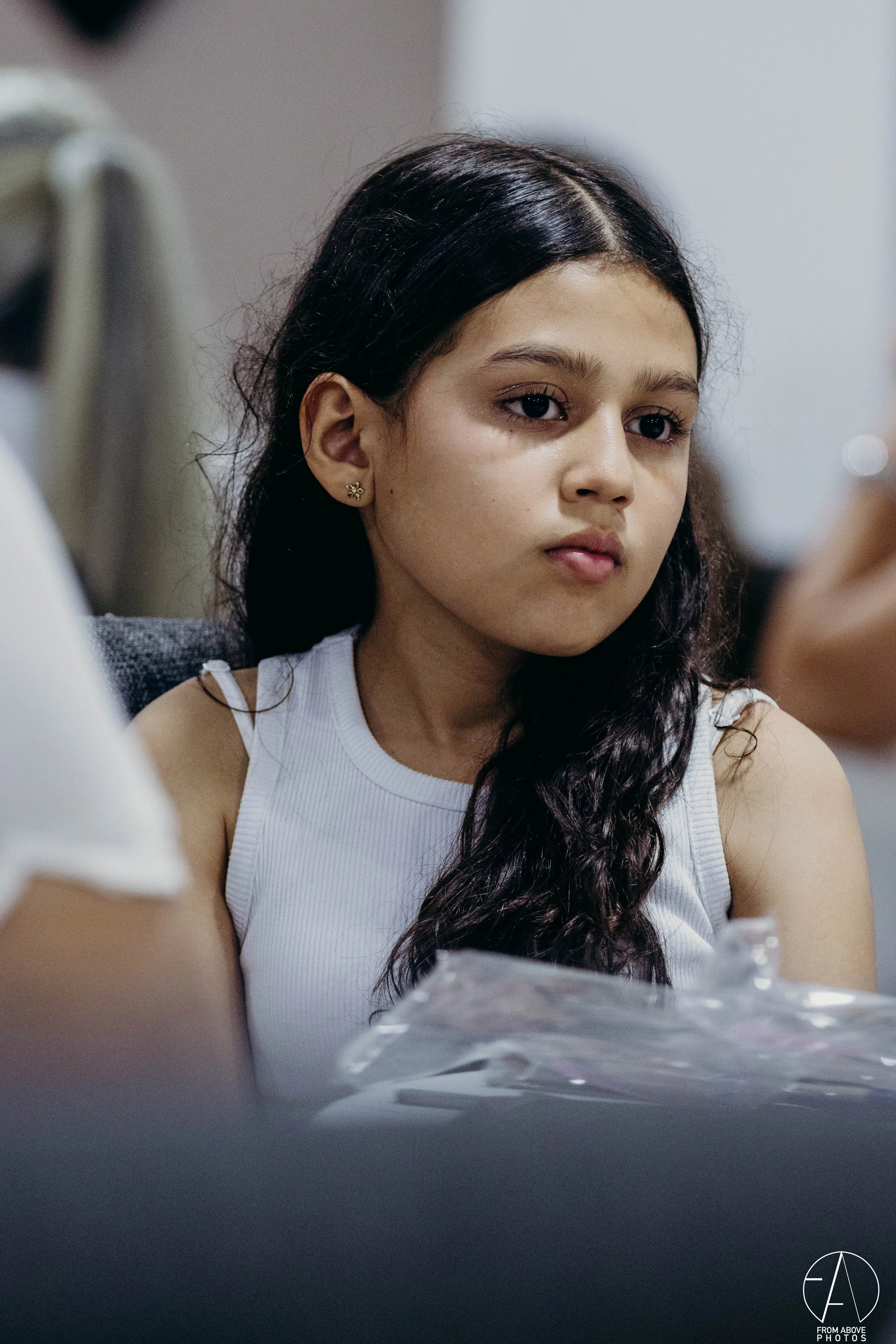 Joven con cabello rizado y piel clara mirando atentamente, sentada con una bolsa de plástico frente a ella.
