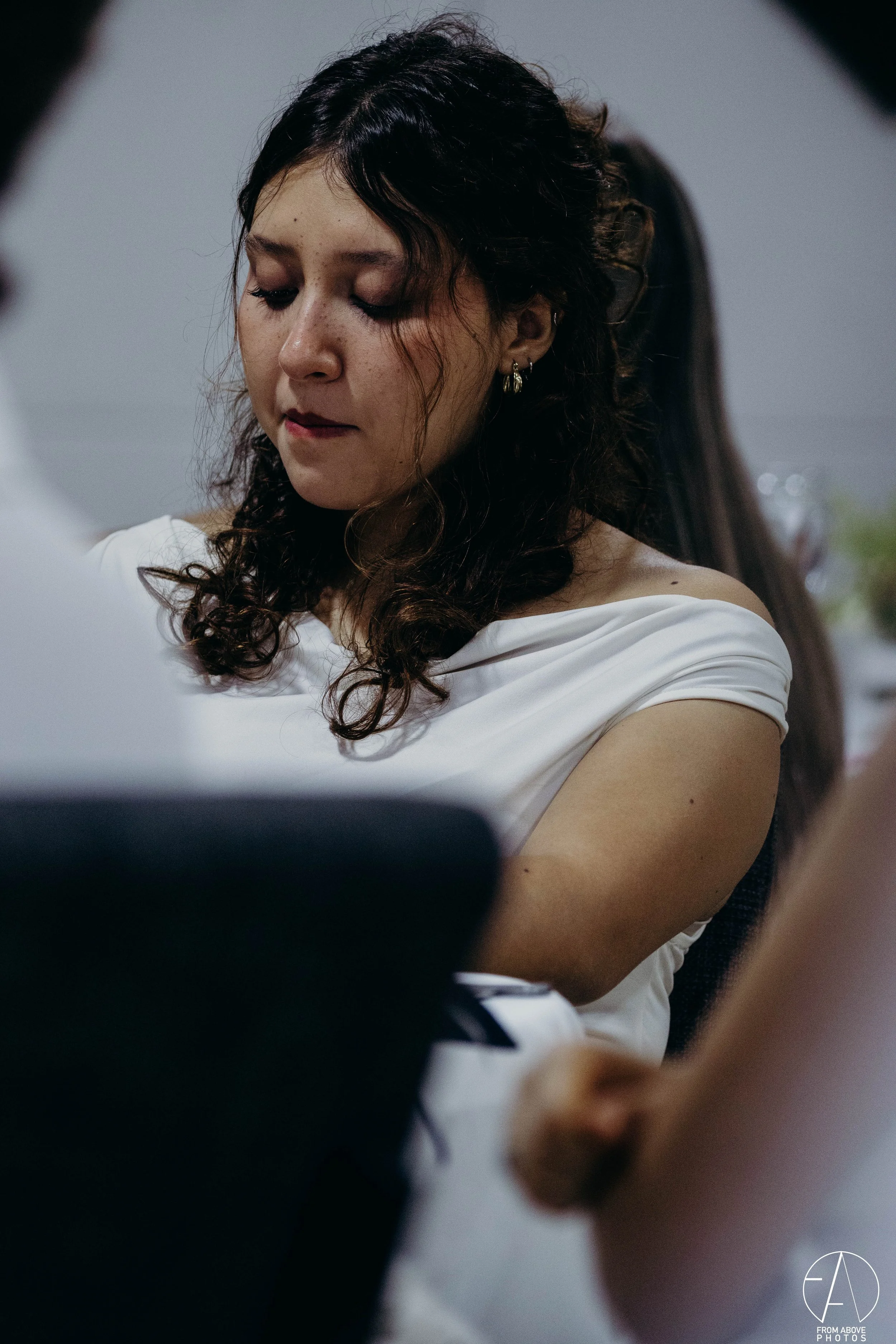 Mujer con cabello rizado y vestida con blusa blanca en una reunión o evento