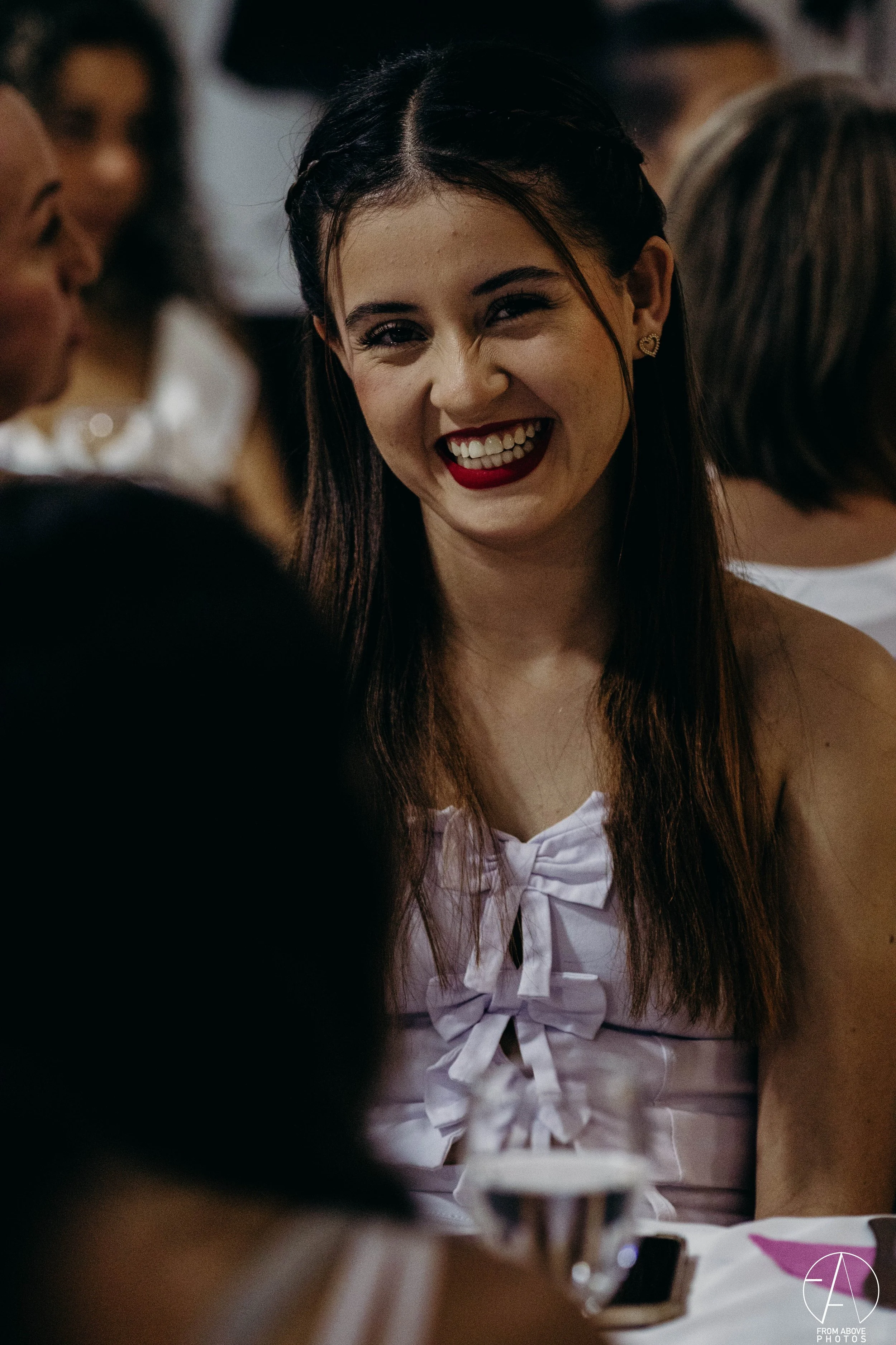 Una joven chica riendo con un fondo de otras personas en un evento social.