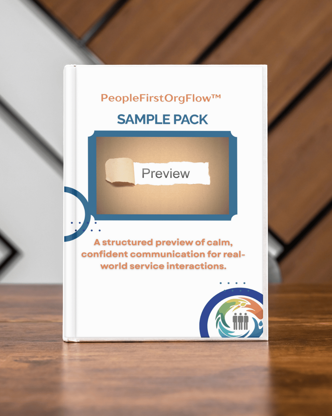 A printed book titled 'PeopleFirstOrgFlow™ SAMPLE PACK' with a subtitle 'Preview' on a wooden table, featuring a logo at the bottom right corner.