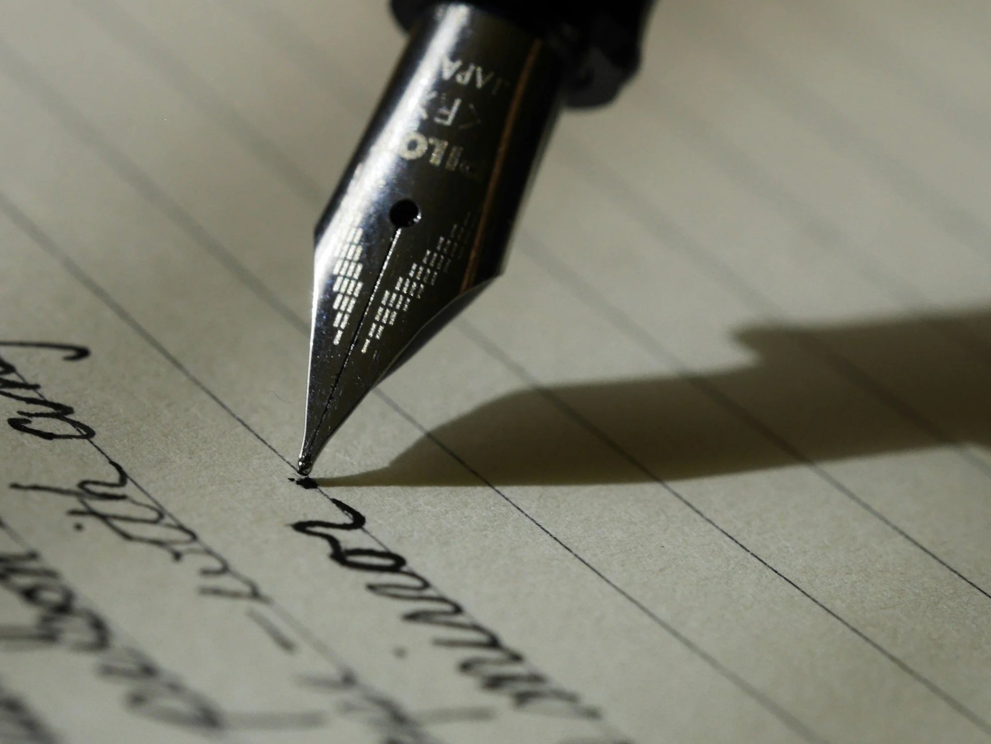 Close-up of a fountain pen writing on lined paper.