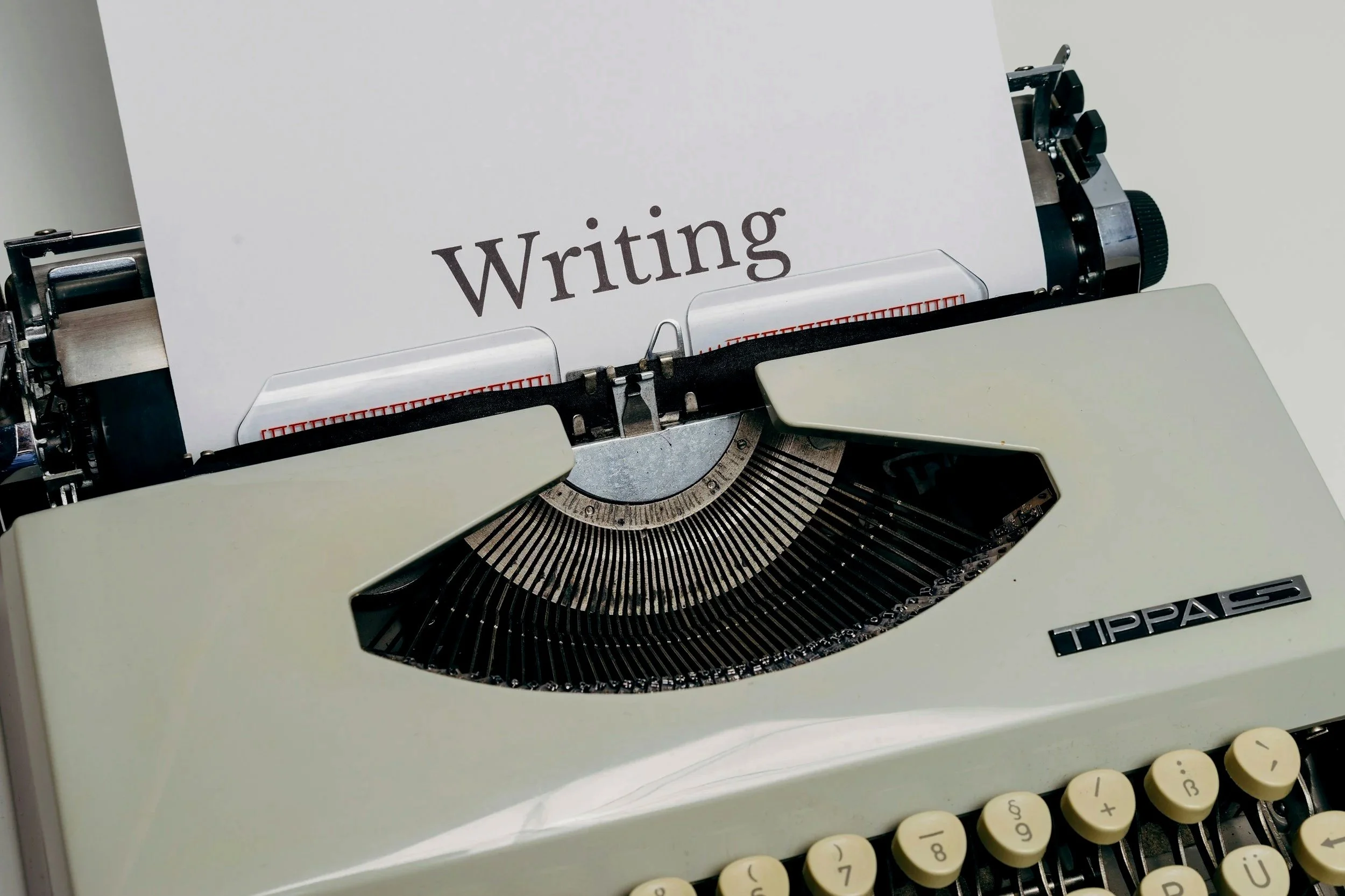 A vintage typewriter with the word 'Writing' on a sheet of paper, showing the machine's keys and paper holder.
