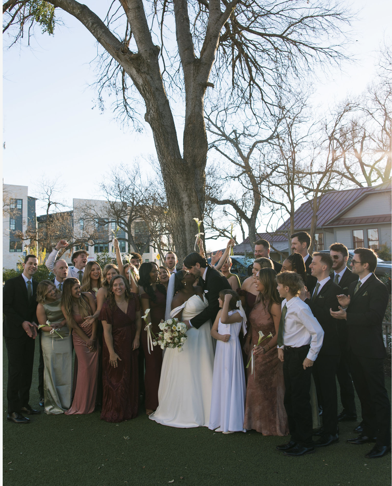 Back view of a woman in an elegant strapless white dress with a lace-up back and large bow, wearing a hat with netting, at a formal event.