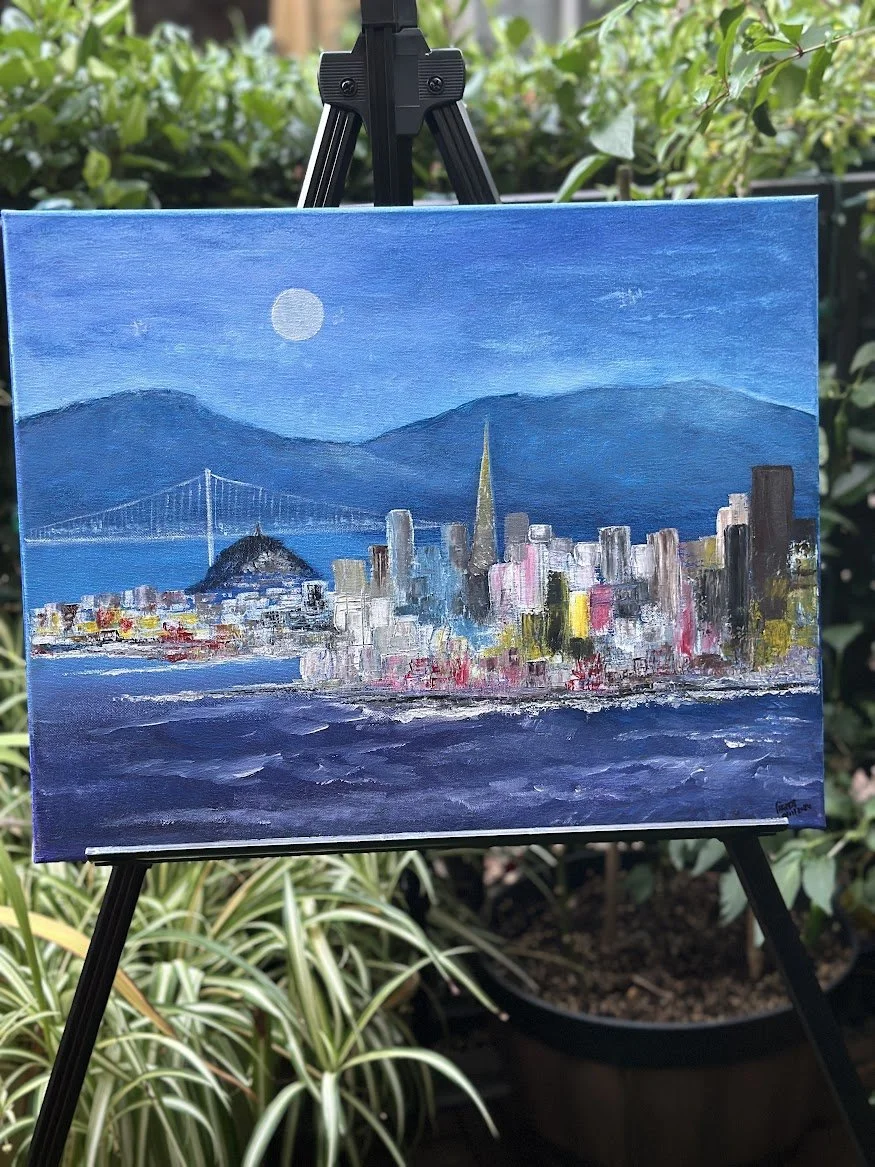 “A moonlit portrait of San Francisco, where the city’s skyline glows softly against the deep blue of the bay. The bridge stretches gracefully toward the hills, and the water shimmers with textured reflections, capturing the quiet magic of the city at