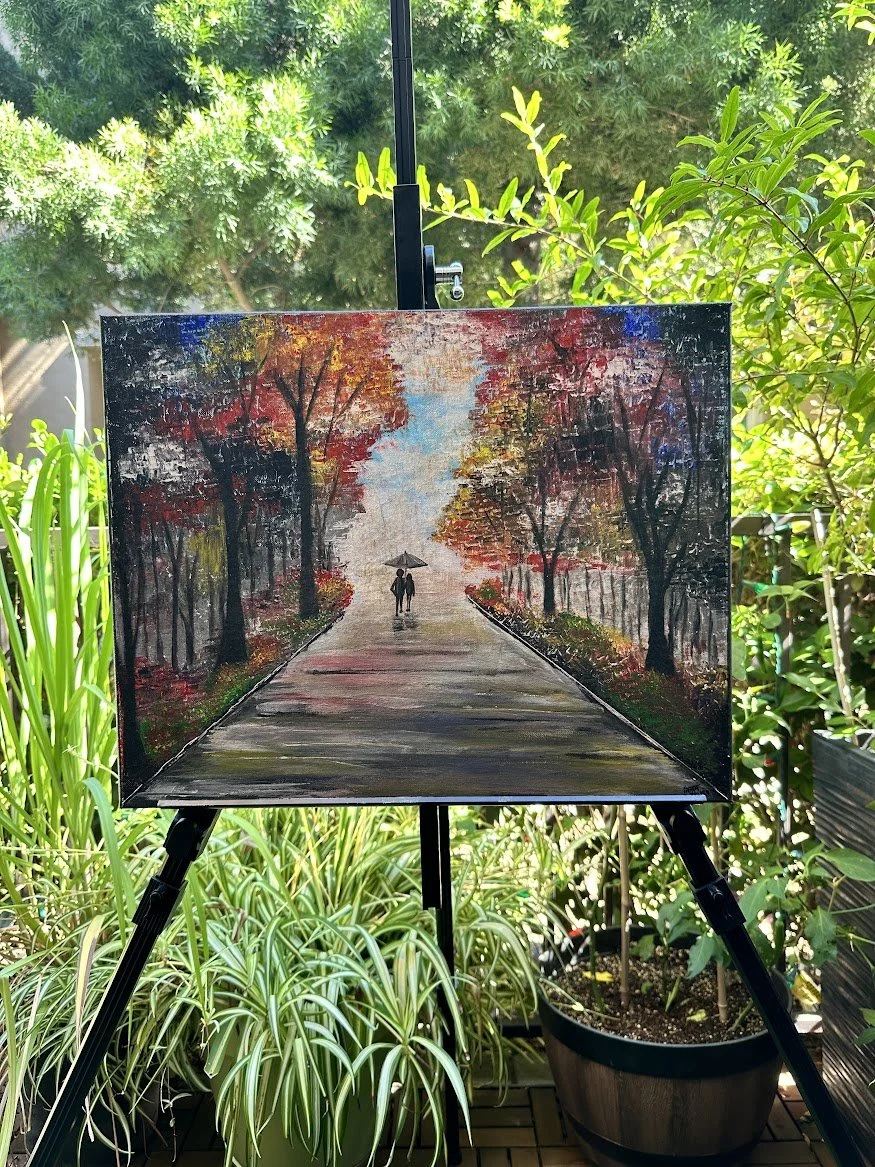 “With rich autumn colors rising on either side, the long path draws the viewer toward a couple walking together into the light. The textured trees and reflective ground evoke comfort, nostalgia, and quiet companionship.” - painting by Neil Banerjee