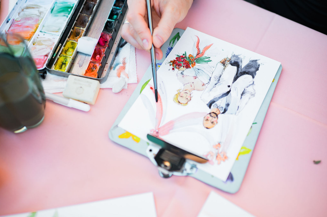 Person watercolor painting of three people, one man and two women, with floral and abstract elements, using a brush on paper.