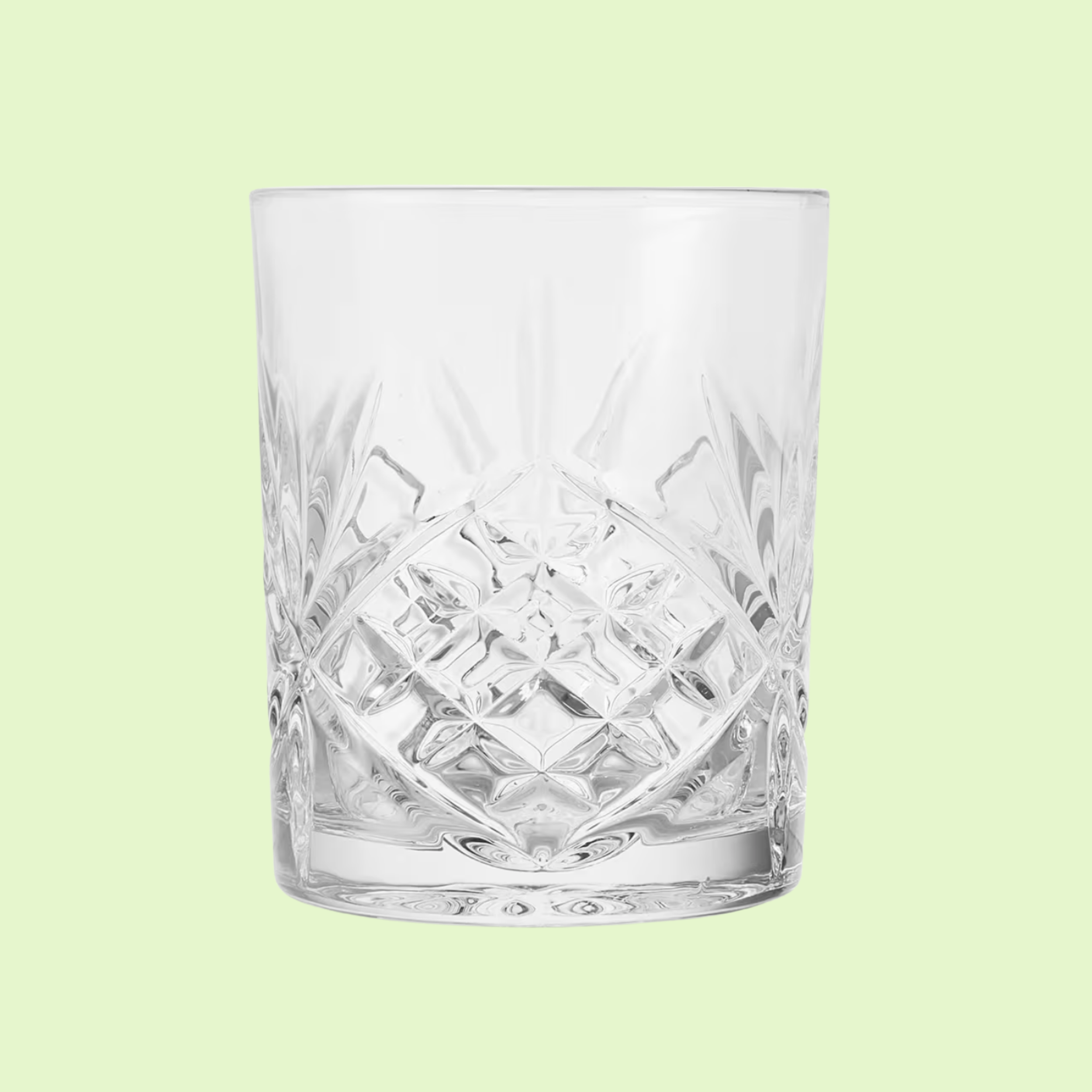 Clear glass tumbler with intricate cut patterns on a light green background.