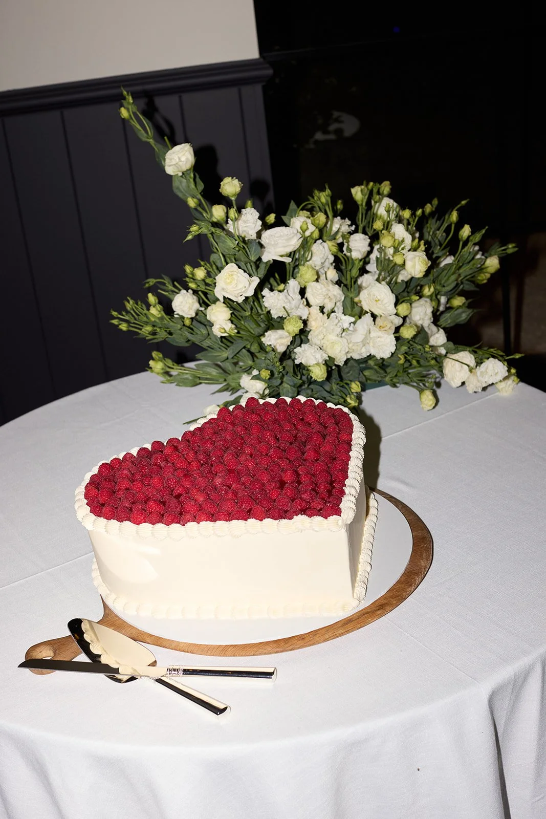 Elegant table setting with white and blue plates, white cloth napkins, glassware including blue-tinted glasses and wine glasses, floral centerpieces with white and green flowers, and a white tablecloth.