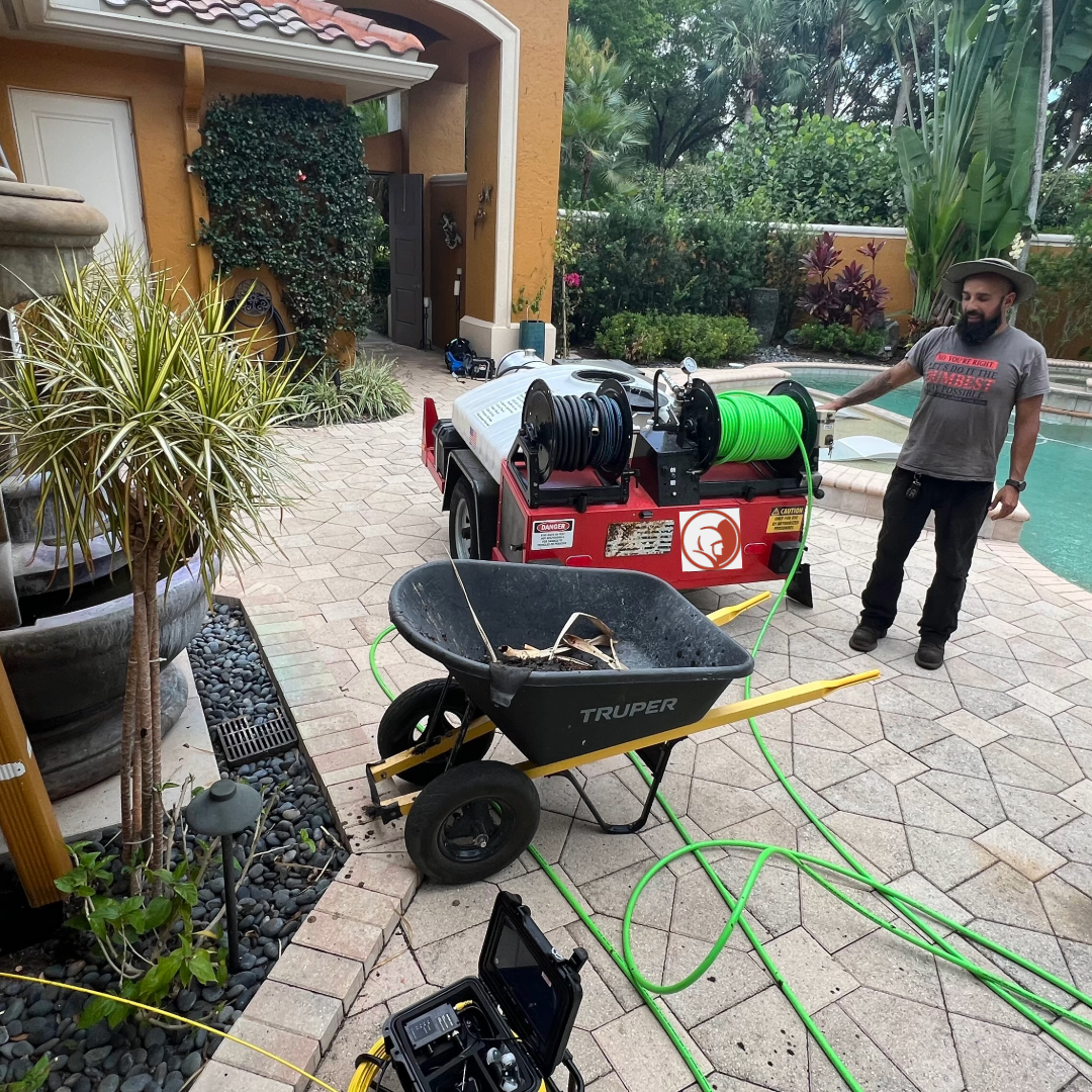 Technicians prepping jetter and debris removal equipment for storm drain cleaning on driveway