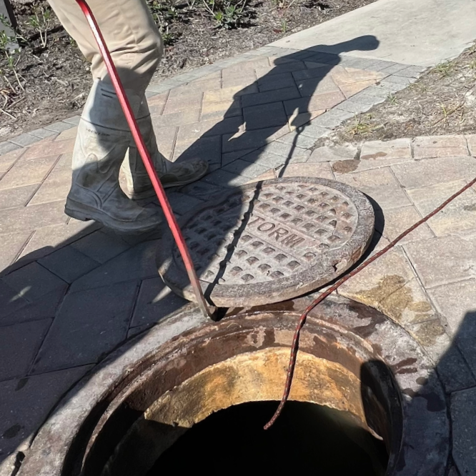 Close up of stormwater inspector inserting a camera rod into a manhole to check for blockages and root intrusion.