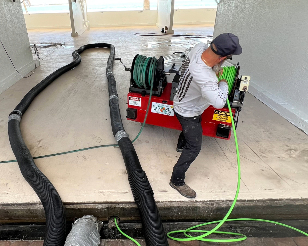 Technician pulling jetter hose while cleaning a parking garage drain system