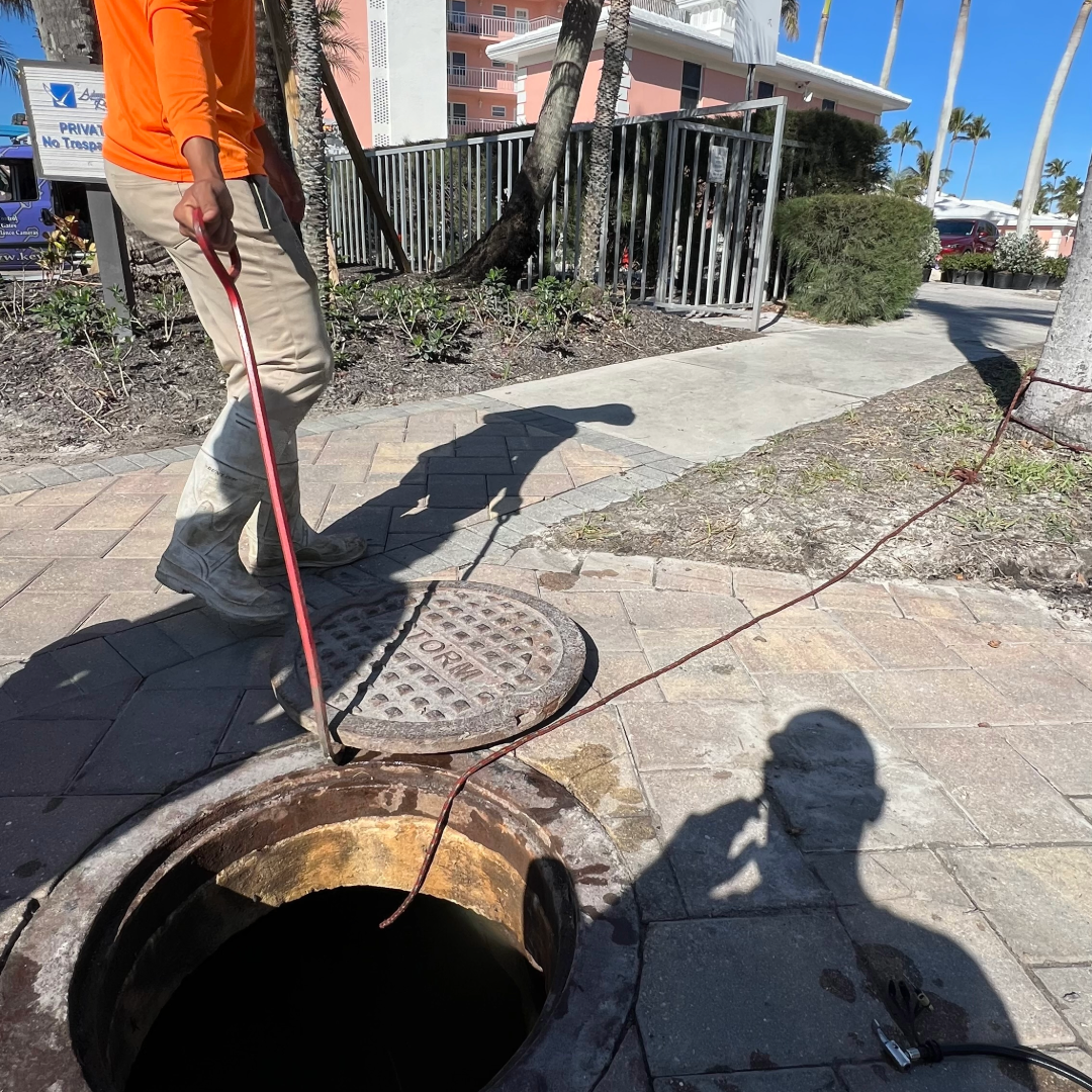 Technician removing roots from manhole during stormwater system maintenance