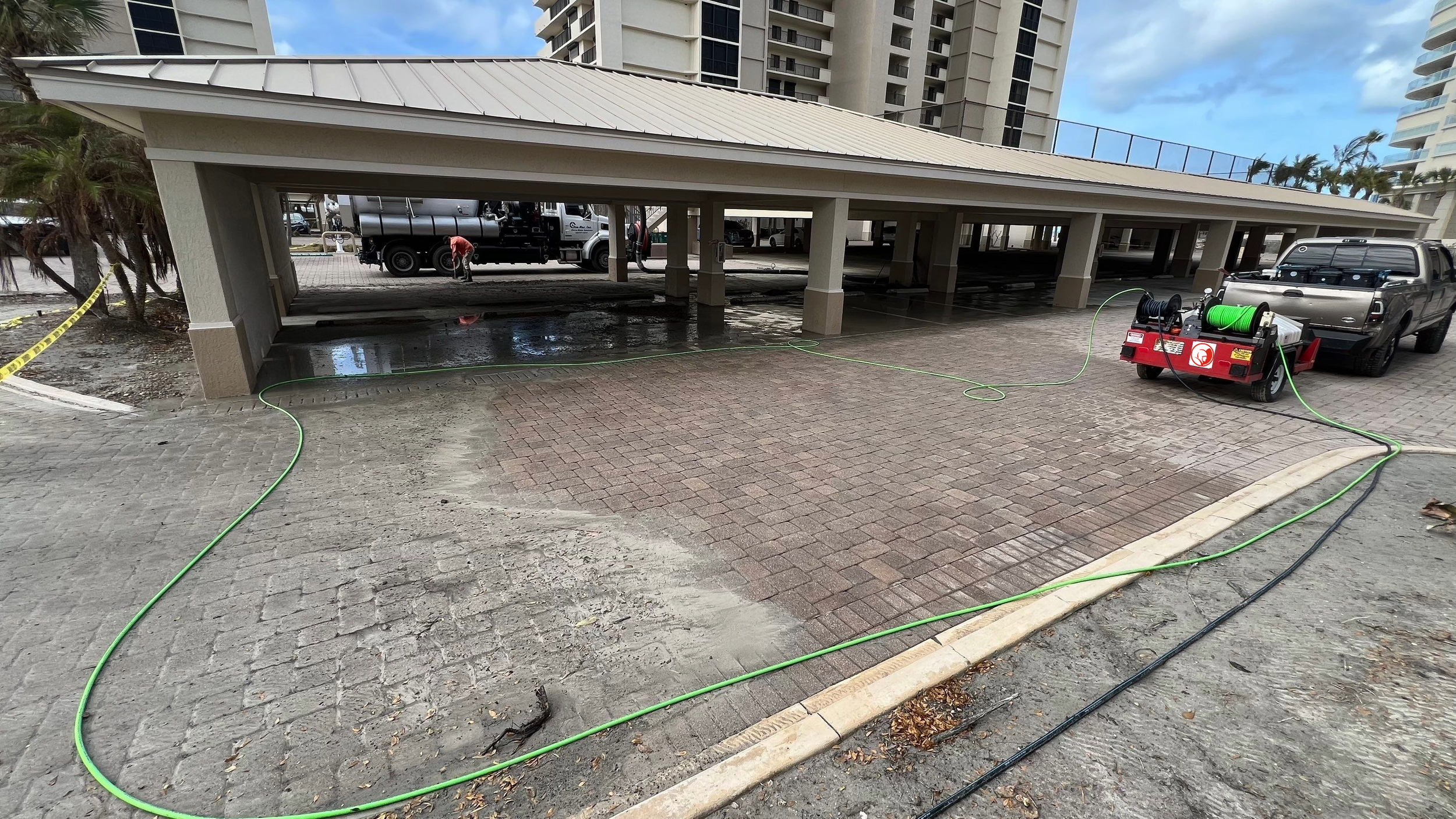 Surface cleaning crew pressure washing a parking garage driveway at a commercial property in Naples, Florida.