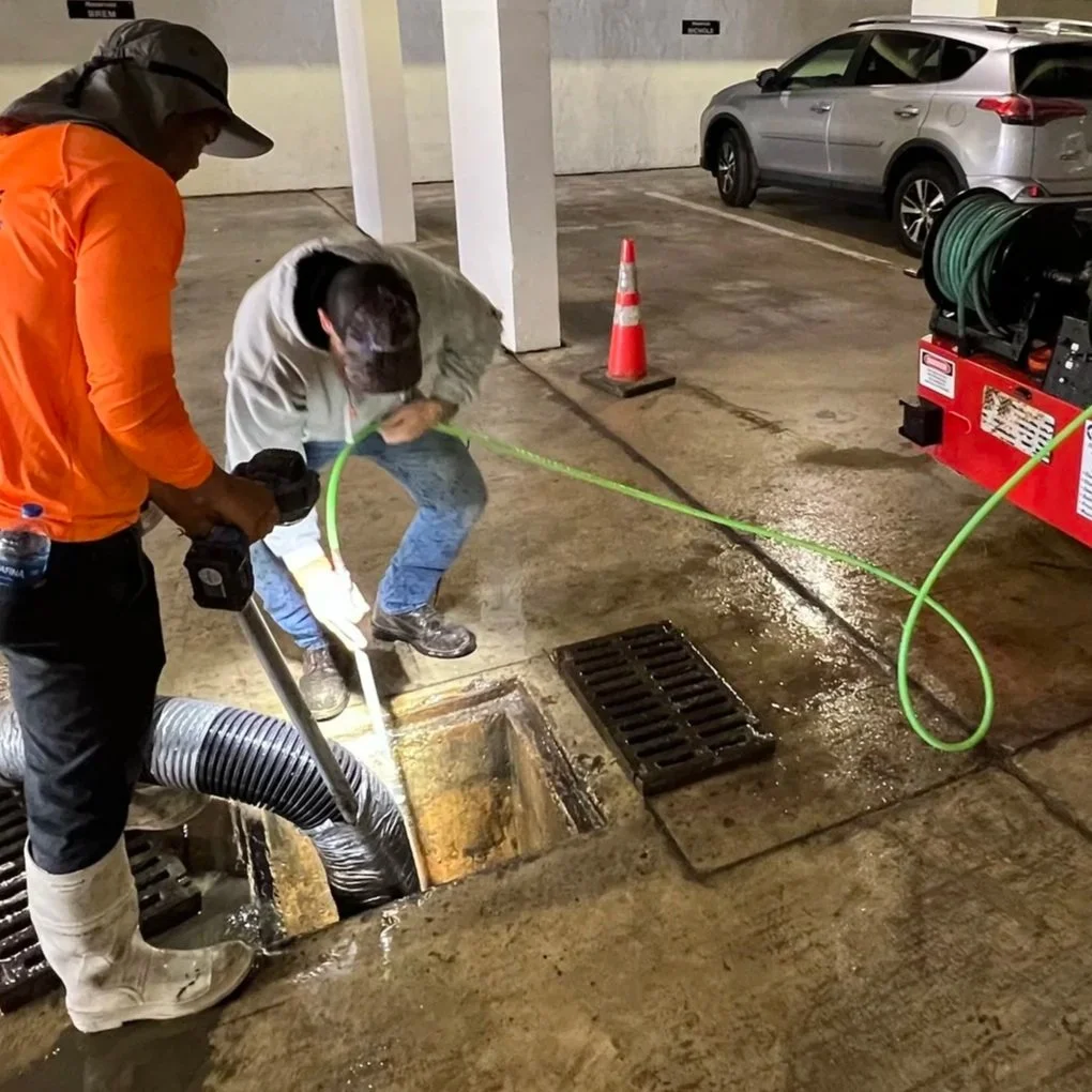 Stormwater technicians jetting and cleaning a catch basin inside a parking garage in Naples, Florida.